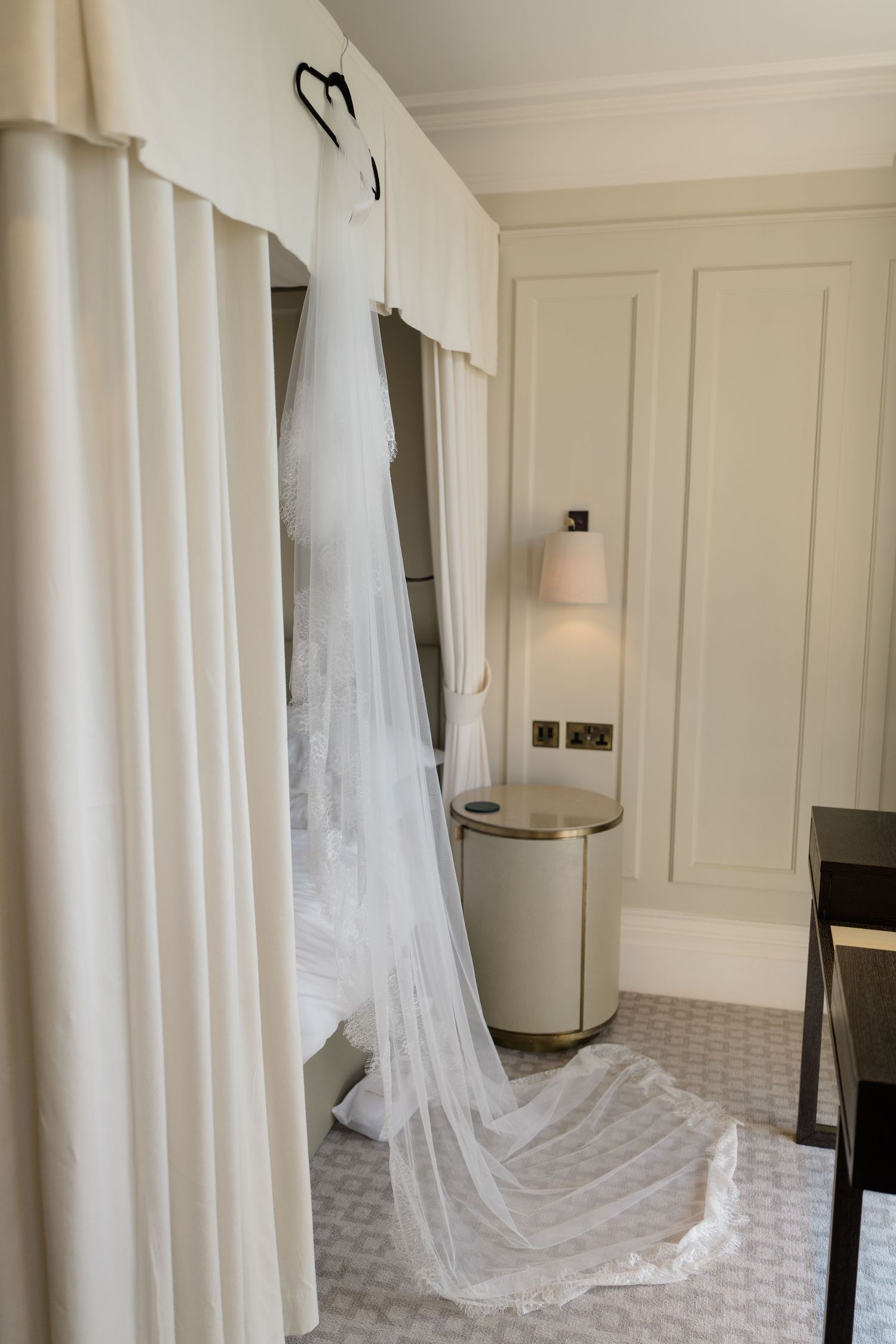 Elegant wedding dress with long veil hanging in a luxury hotel room closet.
