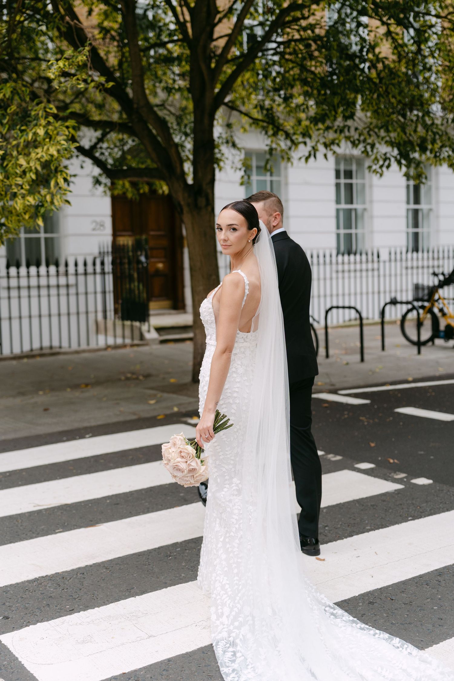 Elegant couple posing on zebra crossing in formal wedding attire.