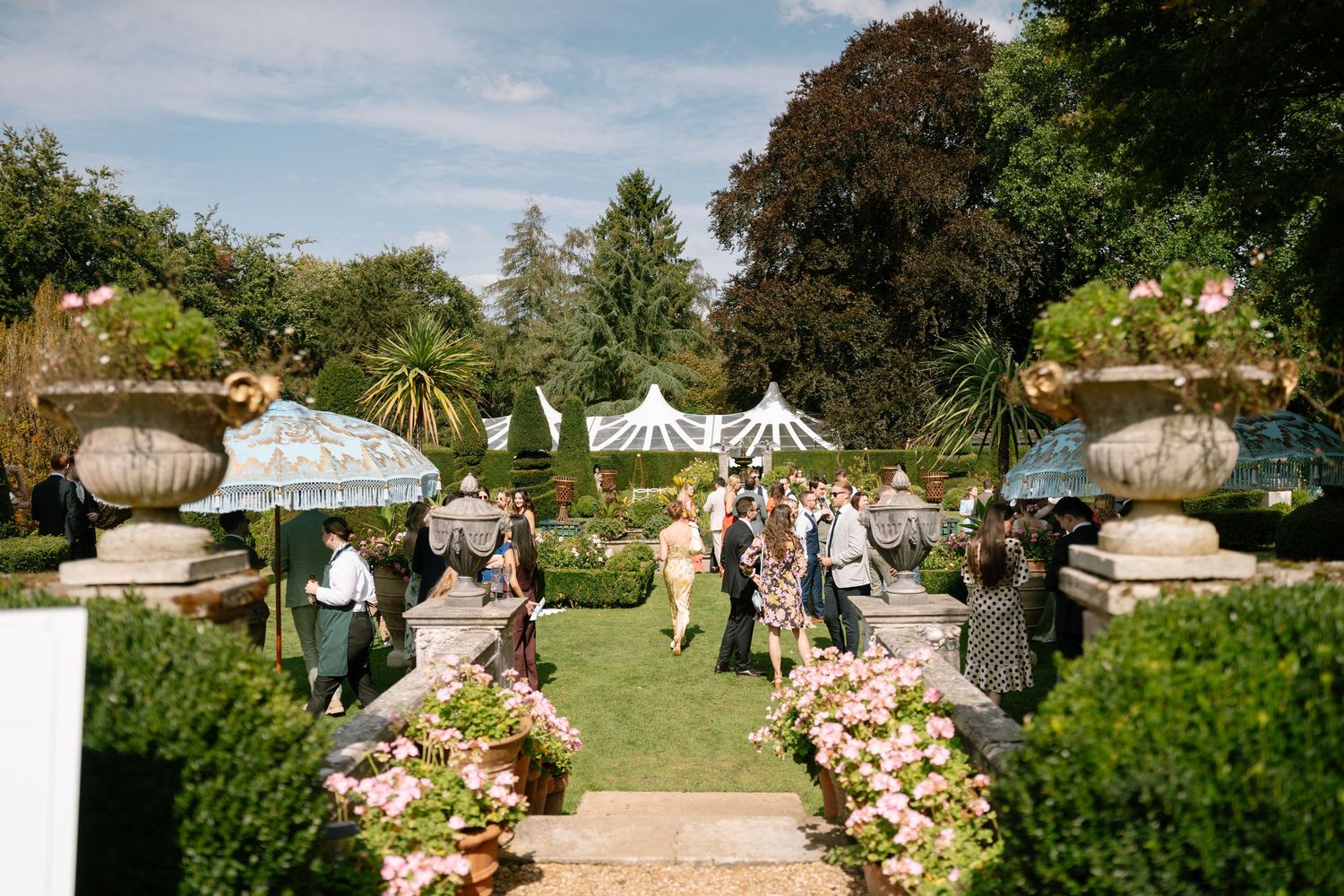 Panoramic view of a garden wedding venue with white tents and floral decorations.