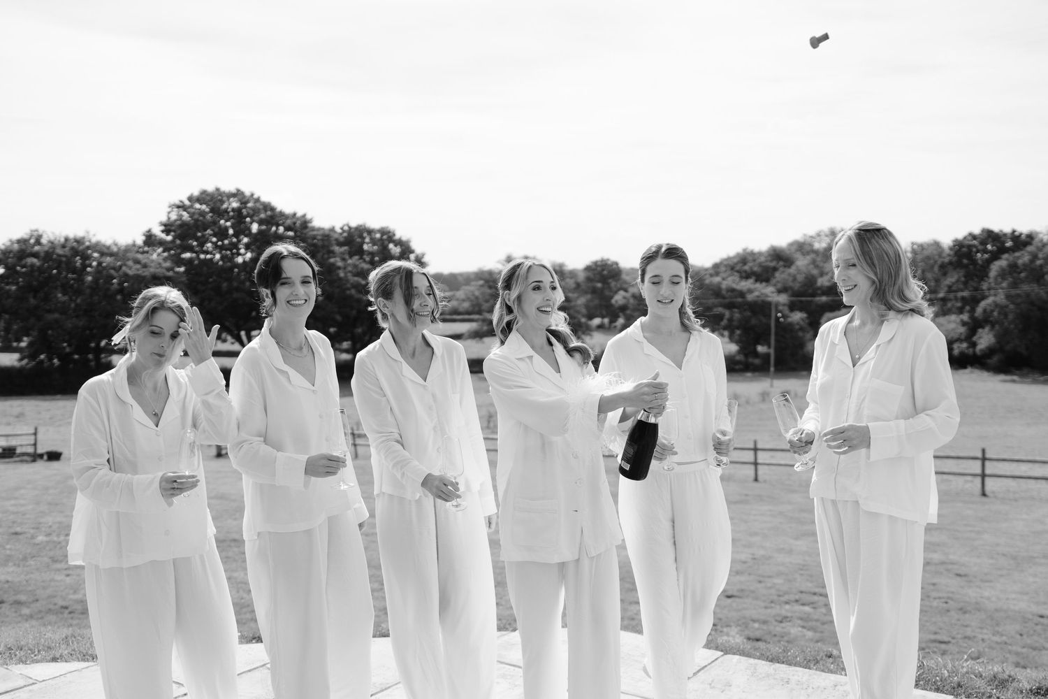 A group of people wearing white robes stand together outdoors in a casual gathering.
