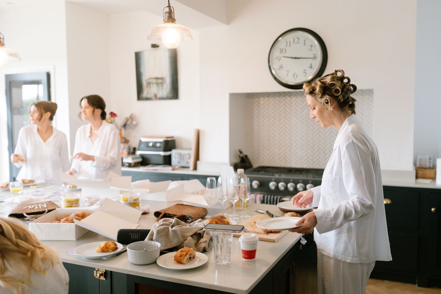 Wedding morning preparations in a bright kitchen with people gathering around a counter.