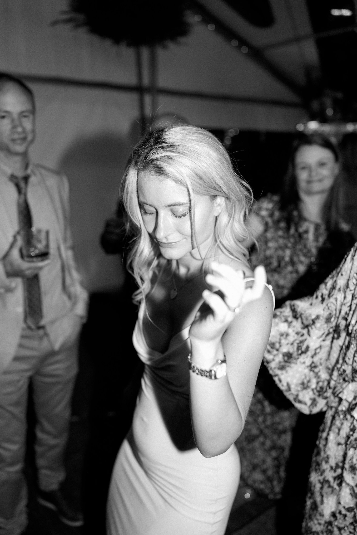 Black and white photo of guests dancing and celebrating at a wedding reception.