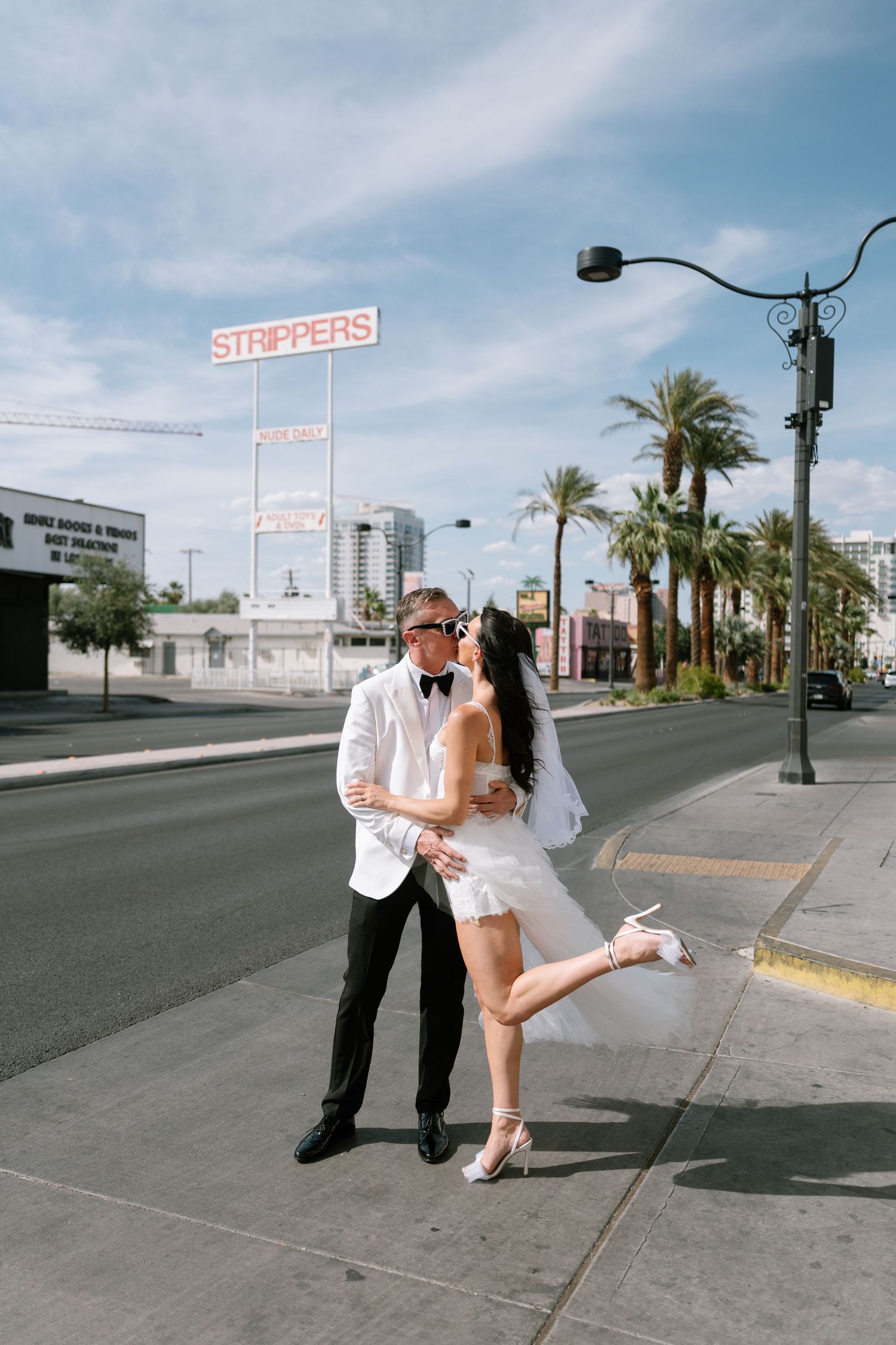 Wedding couple takes romantic photos on an empty Las Vegas street with palm trees.