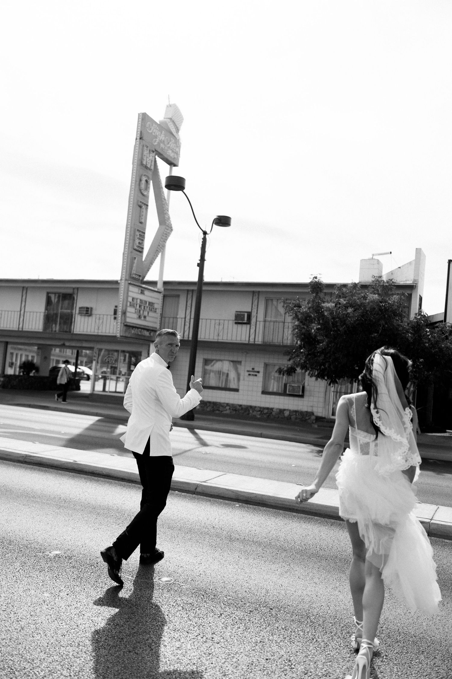 Black and white photo of a couple walking down a street in Las Vegas after their wedding.