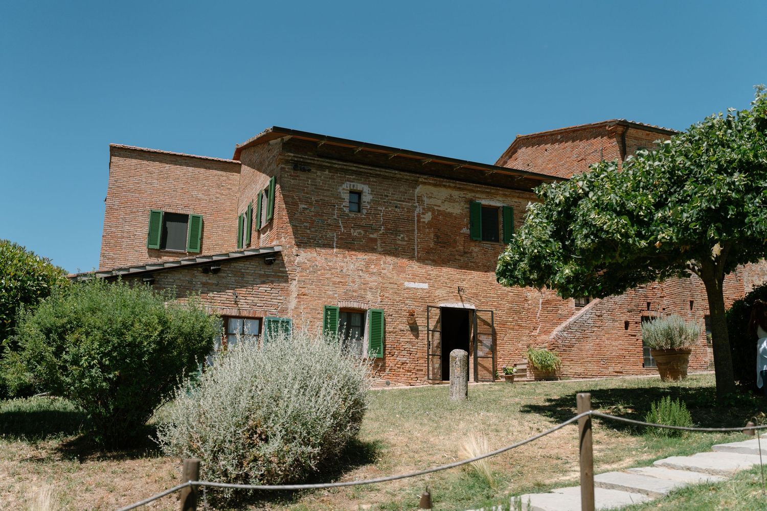 Panoramic view of rustic brick buildings and garden pathways in Tuscany.