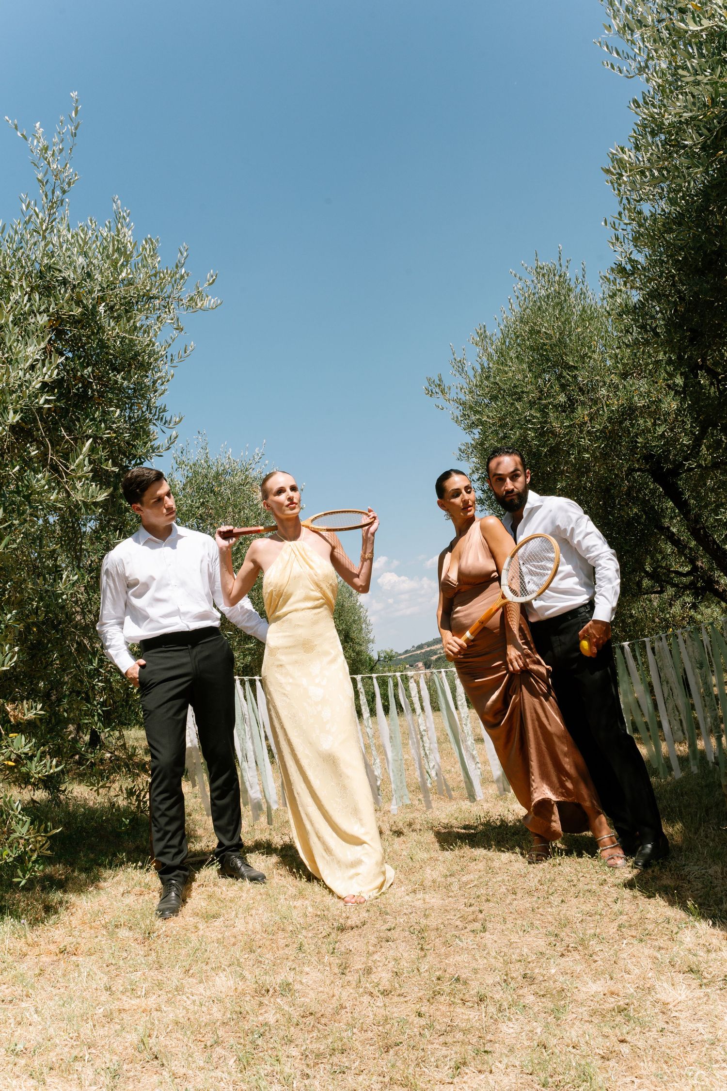 Group enjoying a festive moment in an olive grove under bright blue sky.