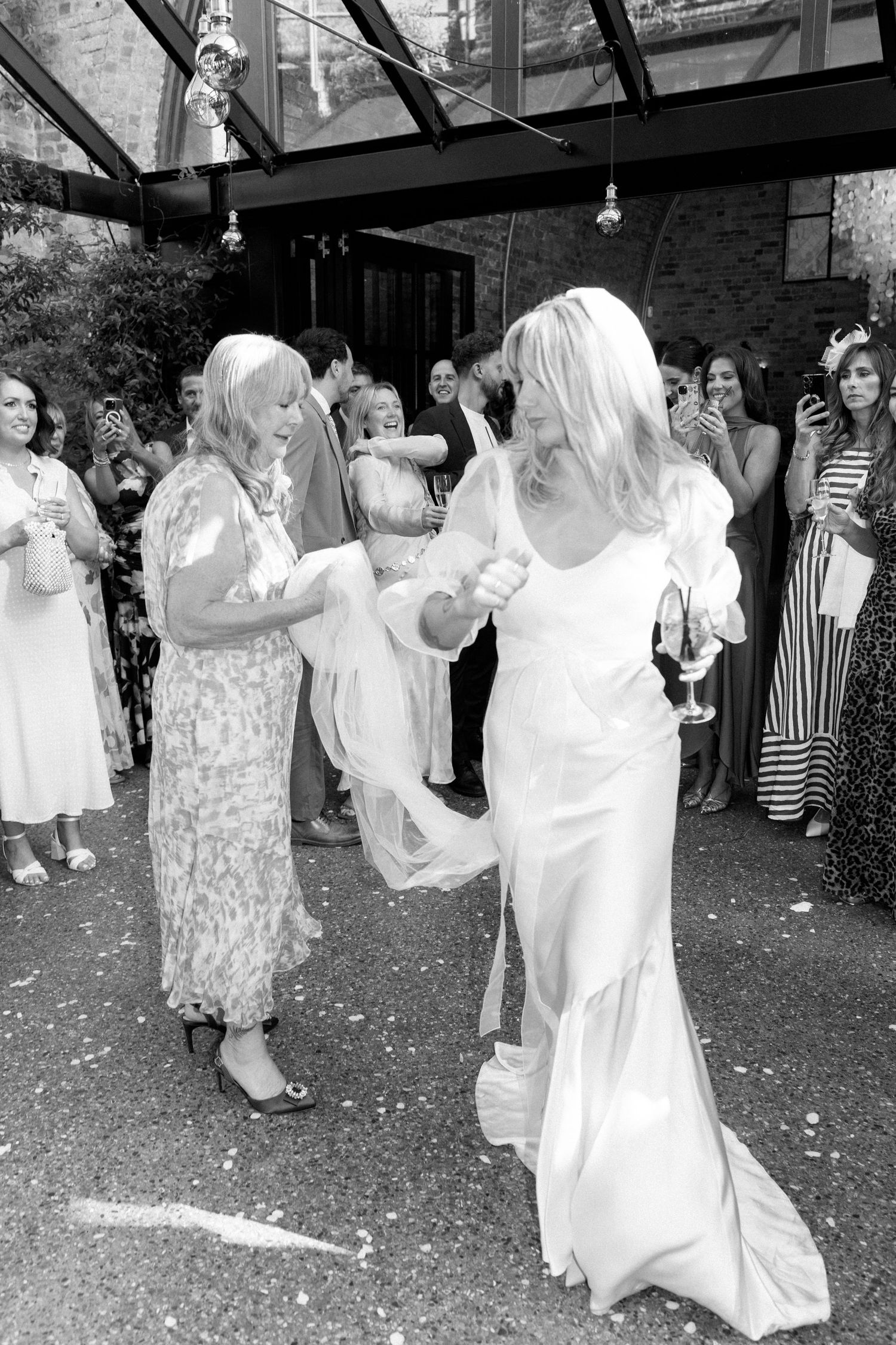 Wedding guests dance and celebrate at an indoor reception venue.
