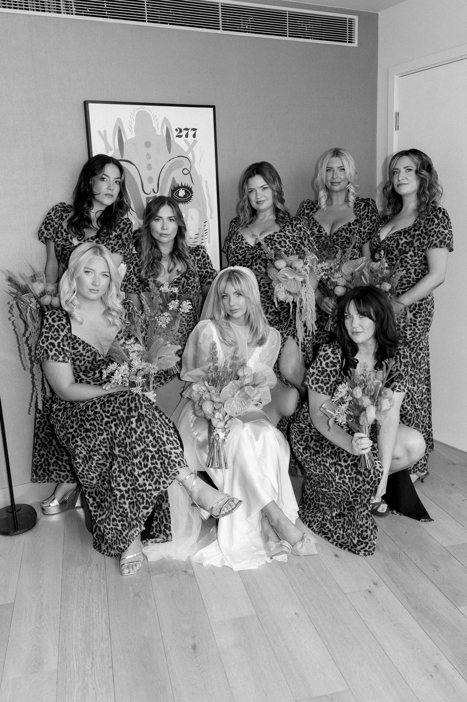Group photo showing people wearing matching leopard print dresses in a bright modern room.
