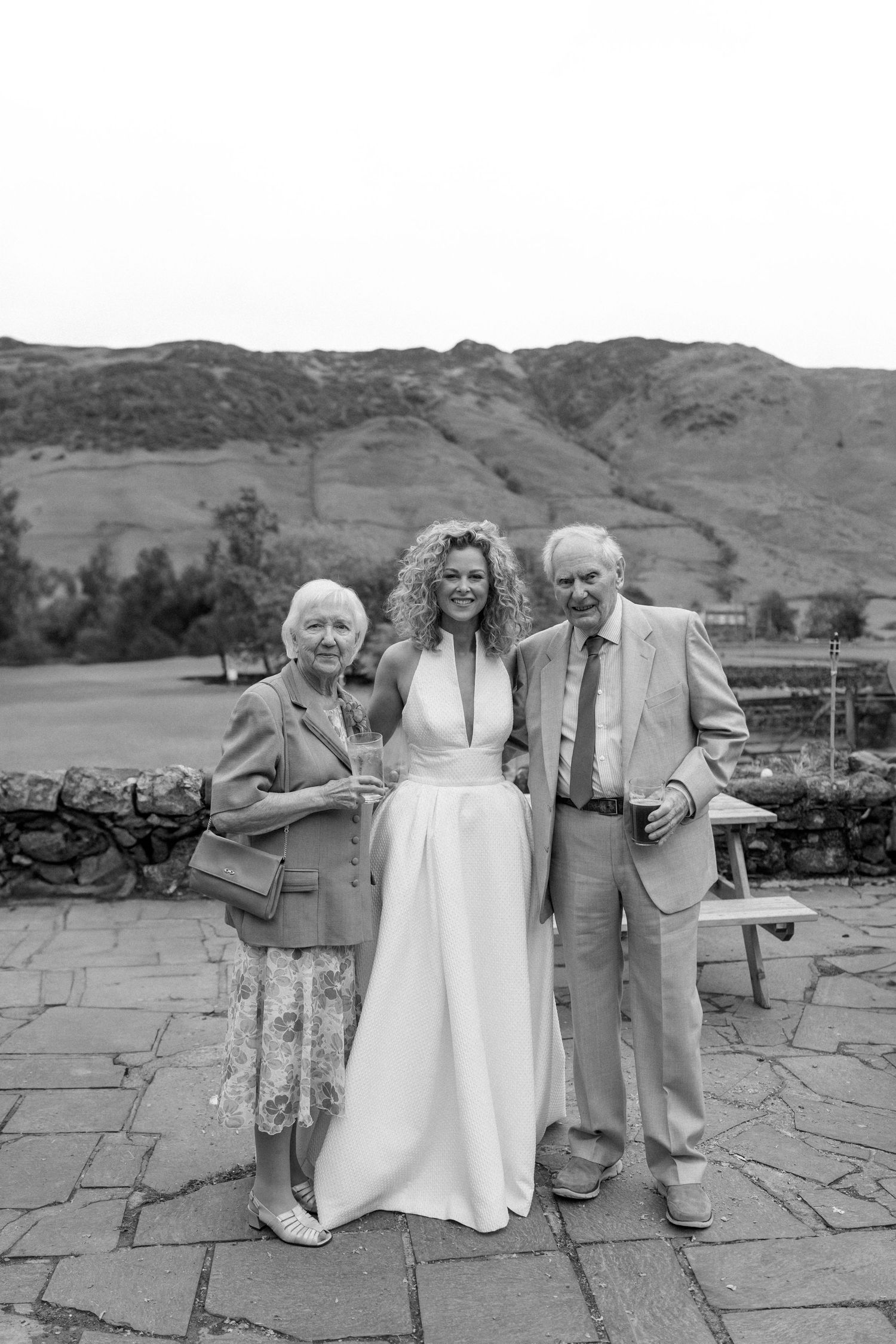 Black and white outdoor wedding portrait against a mountainous Scottish landscape.