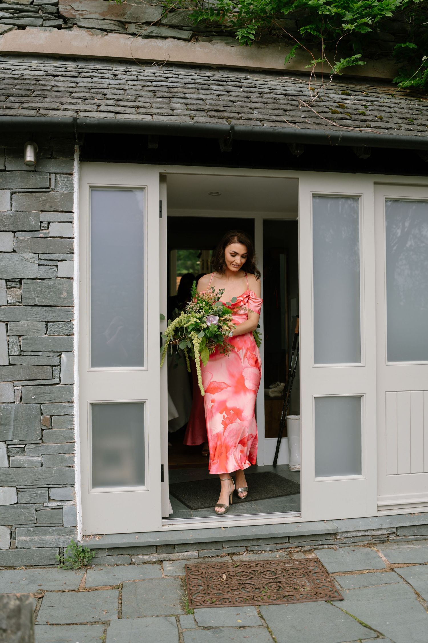 Stone building exterior with people in pink dresses visible through windows.