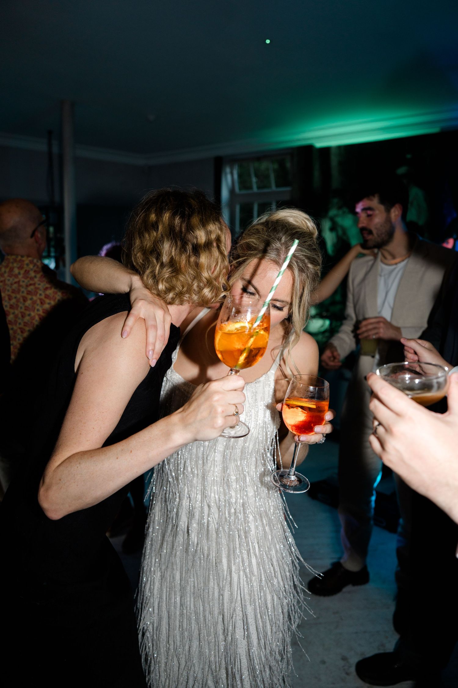 Party scenes with people dancing in silver fringe dress under dark lighting.