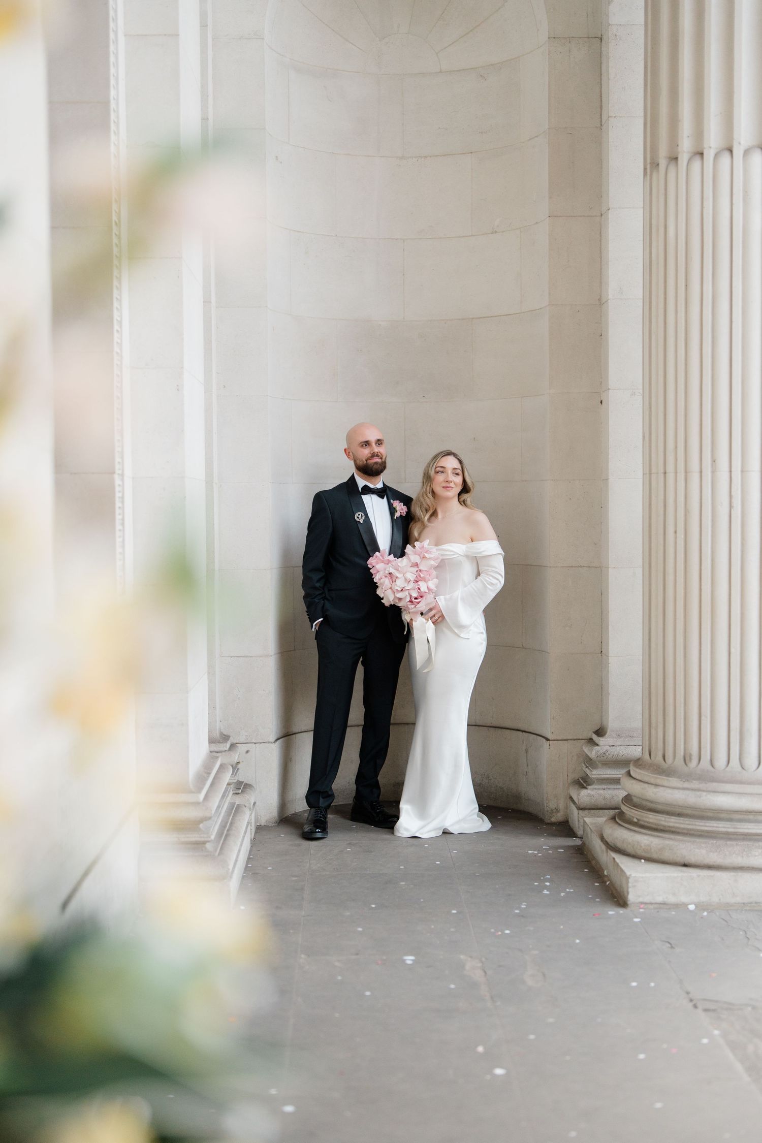 Elegant wedding portrait with couple standing between classical columns.