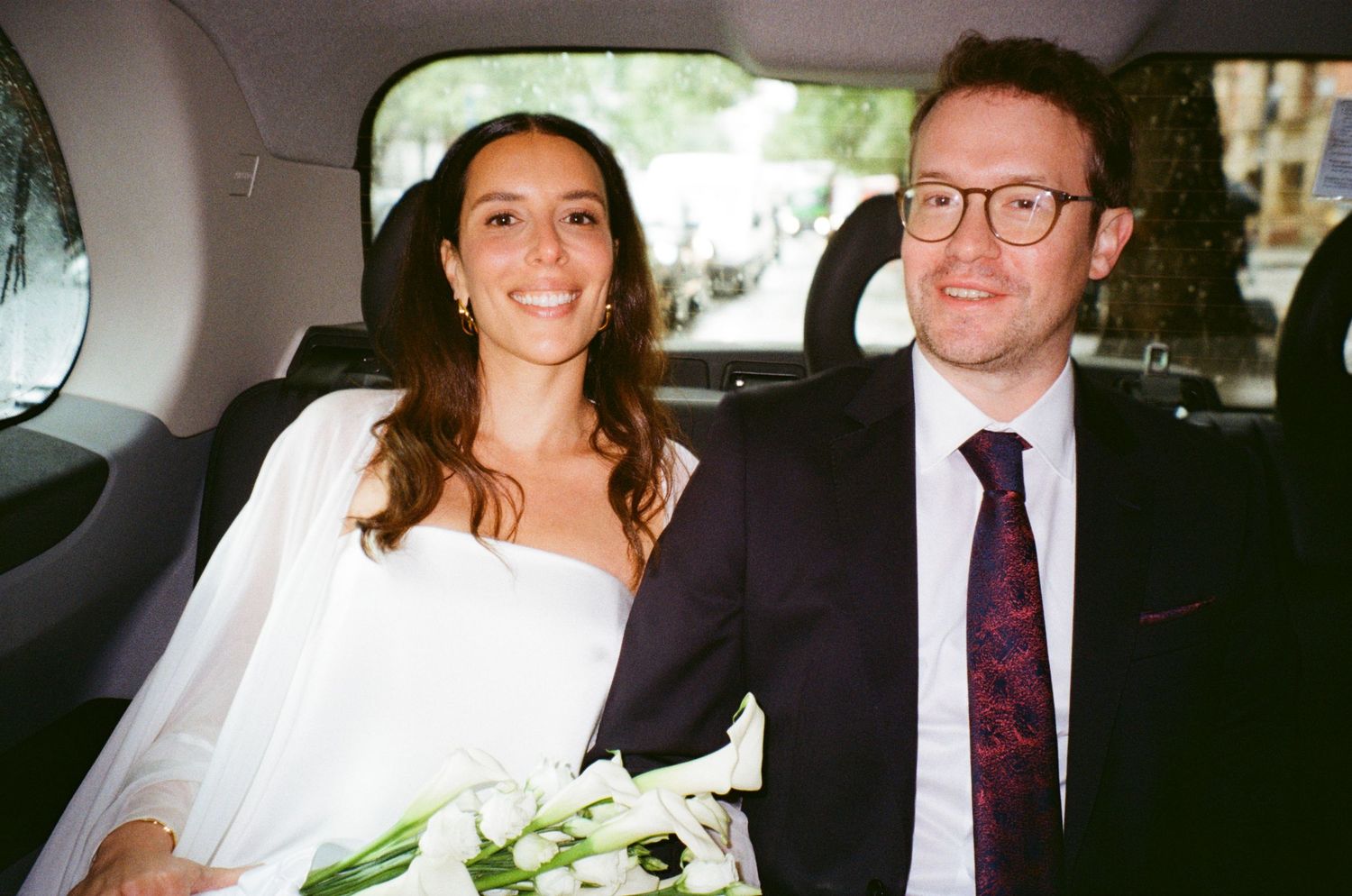 Newlyweds share candid moments in car after wedding ceremony.