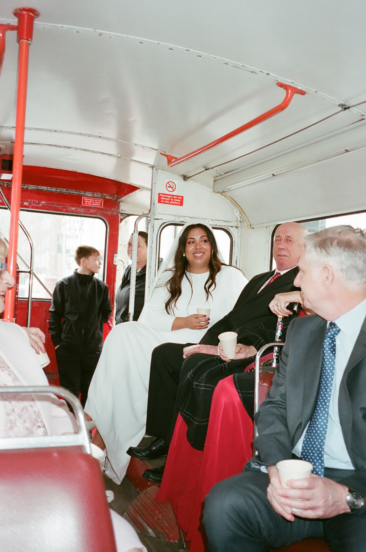 Passengers socialize and converse while riding in the upper level of a classic red double-decker bus interior.