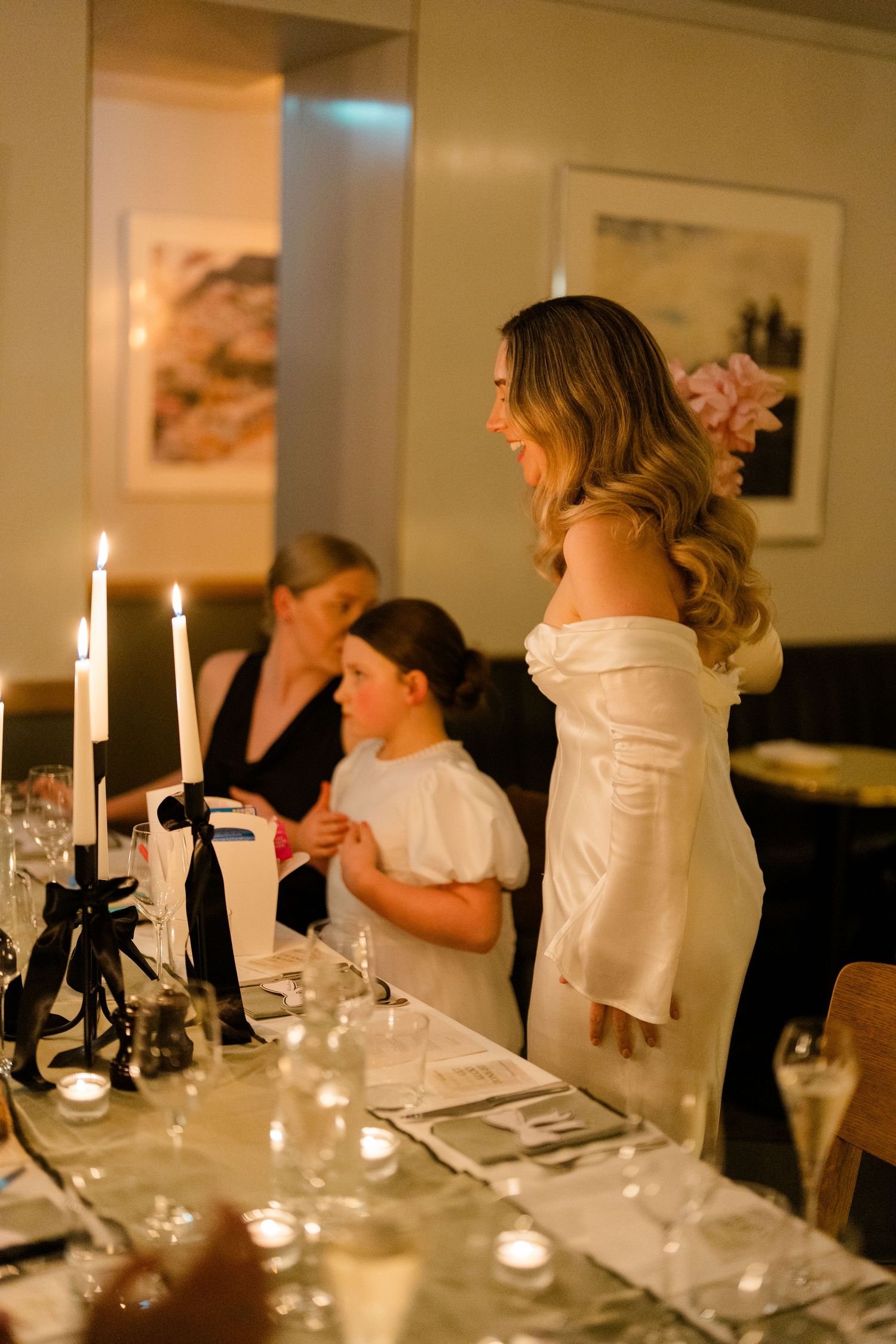 Candlelit wedding reception table with elegant place settings and warm ambient lighting.
