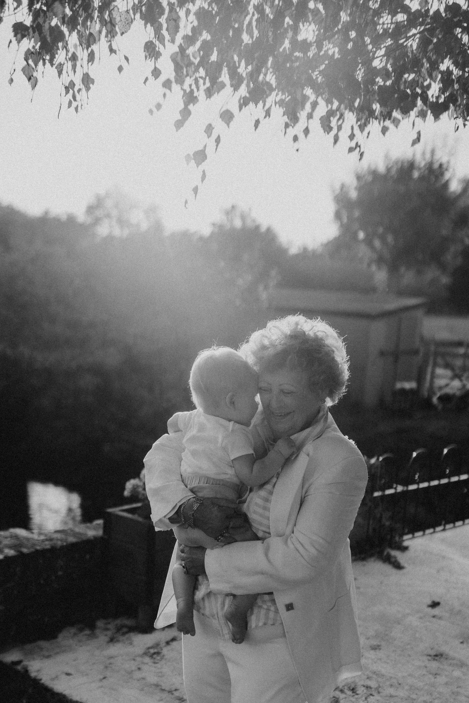 Tender family embrace captured in black and white during golden hour outdoors.