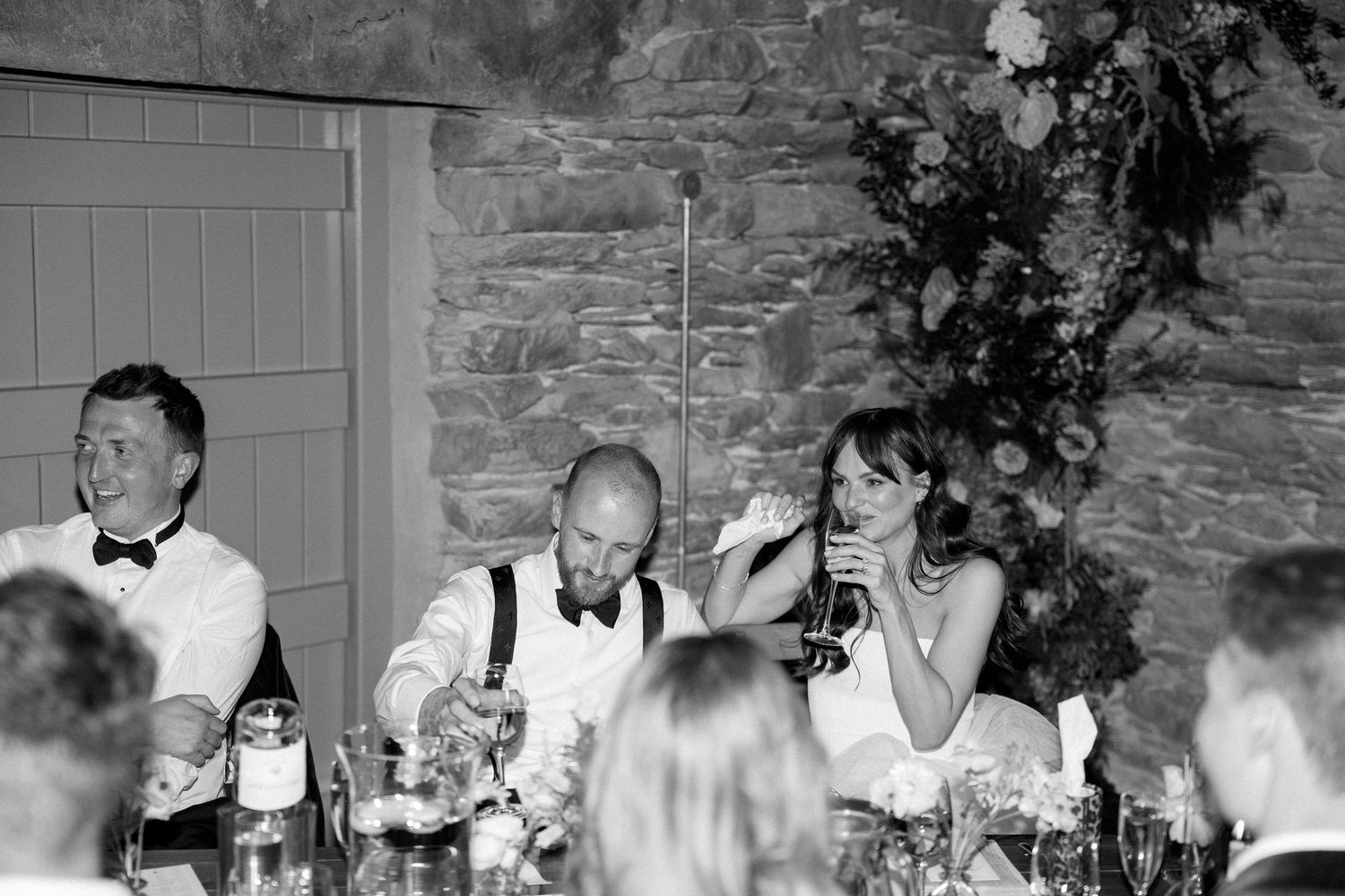 Wedding reception dining setup with stone walls and floral decorations.
