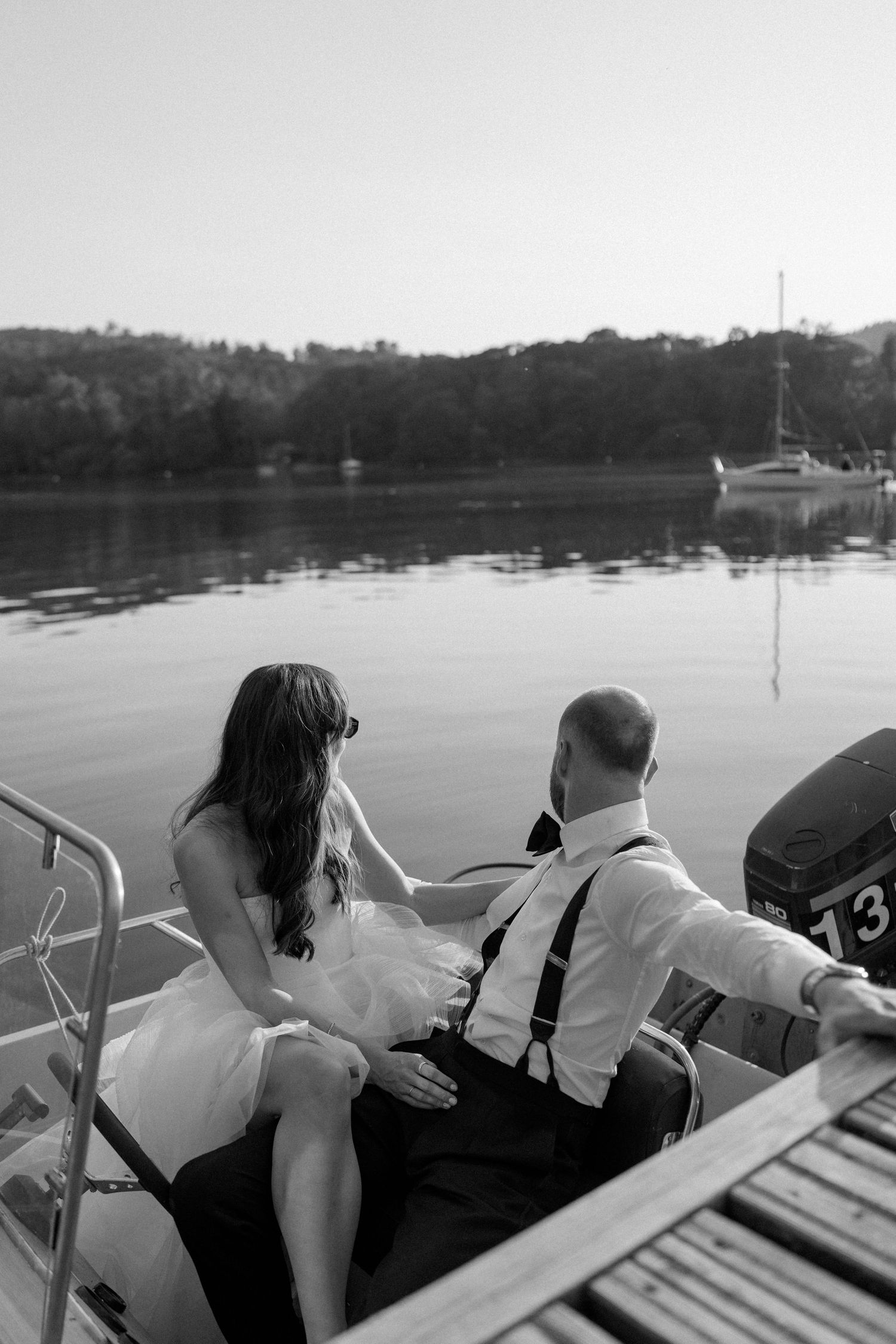 Couple seated in the back of a boat looking out over a serene lake landscape.