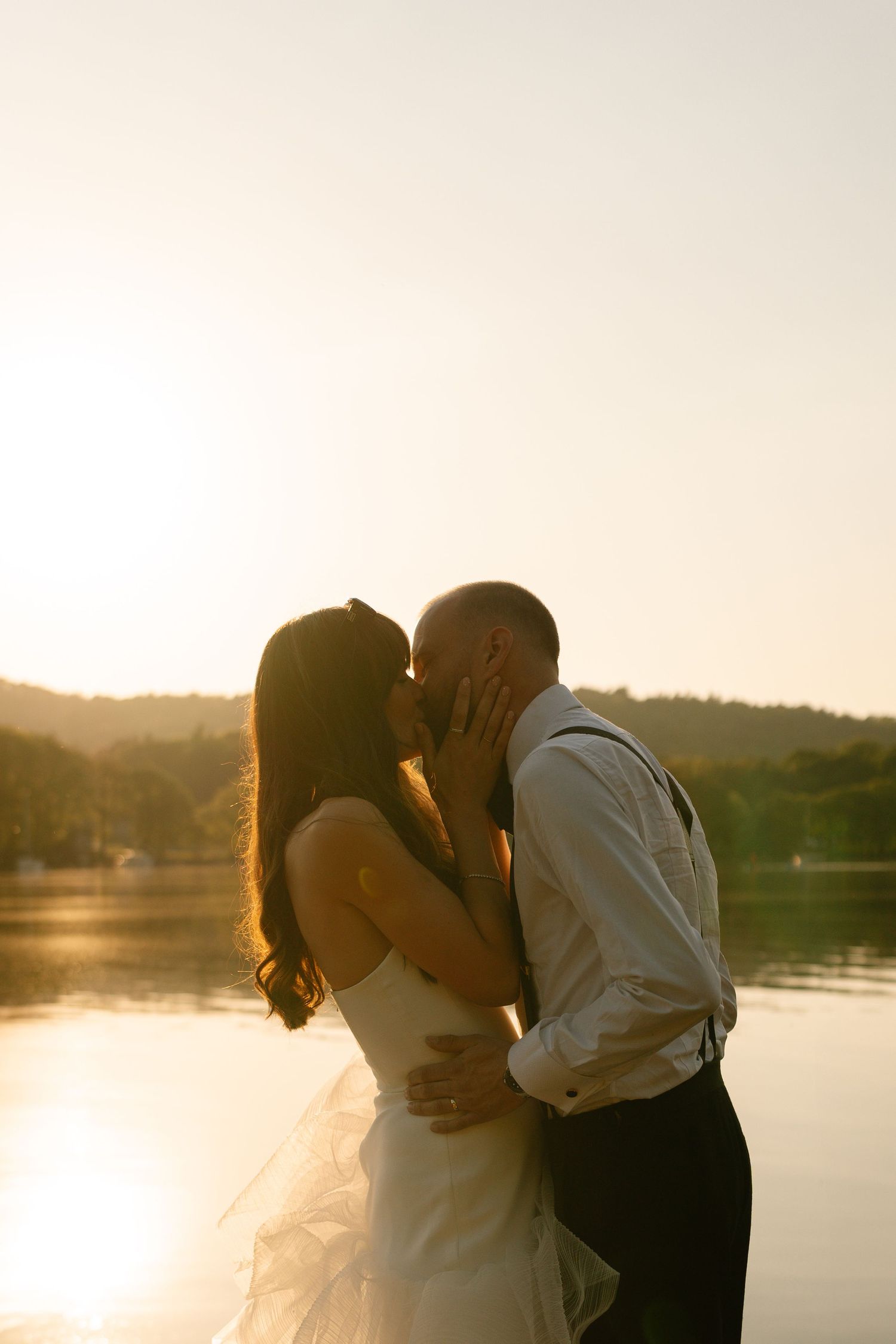 Golden hour wedding portraits with warm backlighting by the lake.
