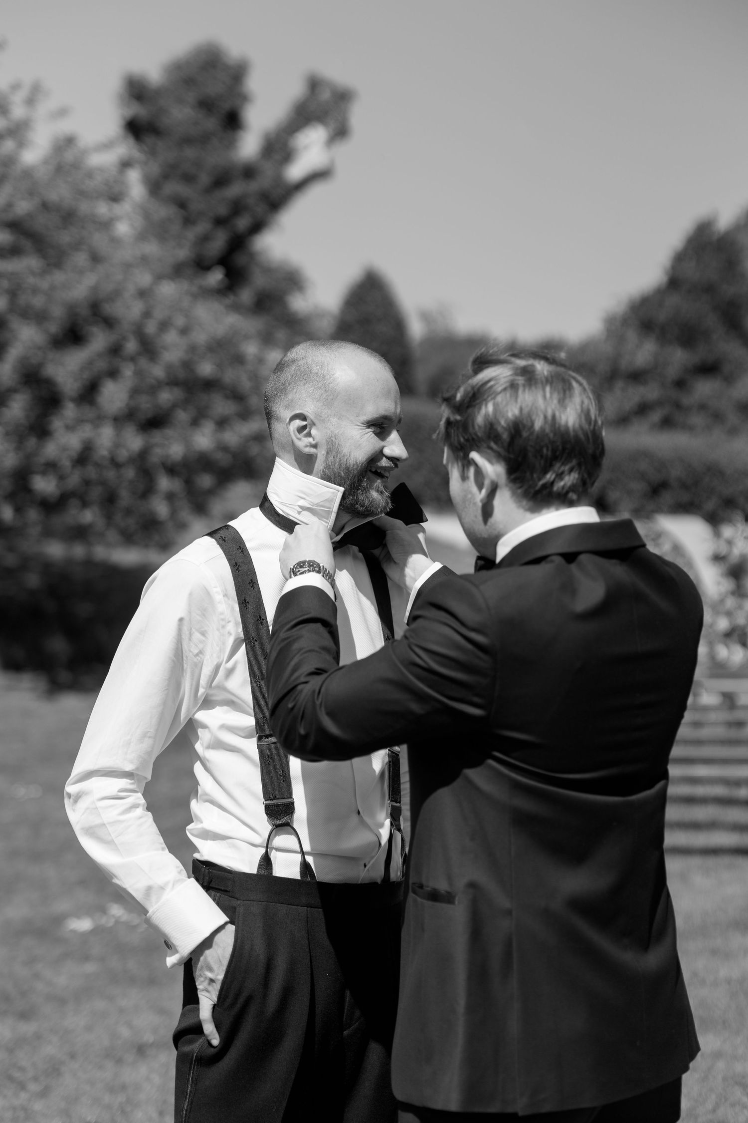 Group in formal wear interacting outdoors on a sunny day.
