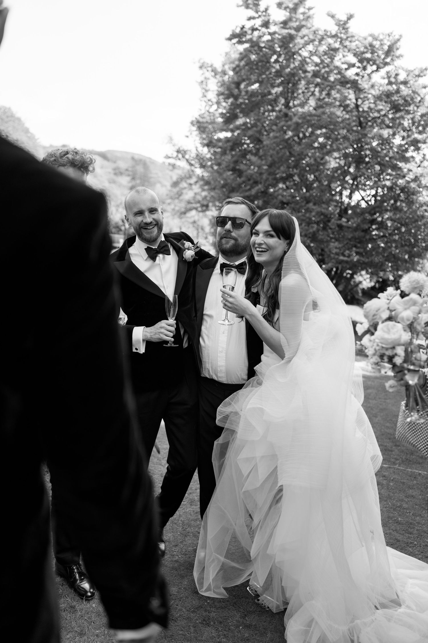 Wedding celebration candid moment with guests laughing outdoors.