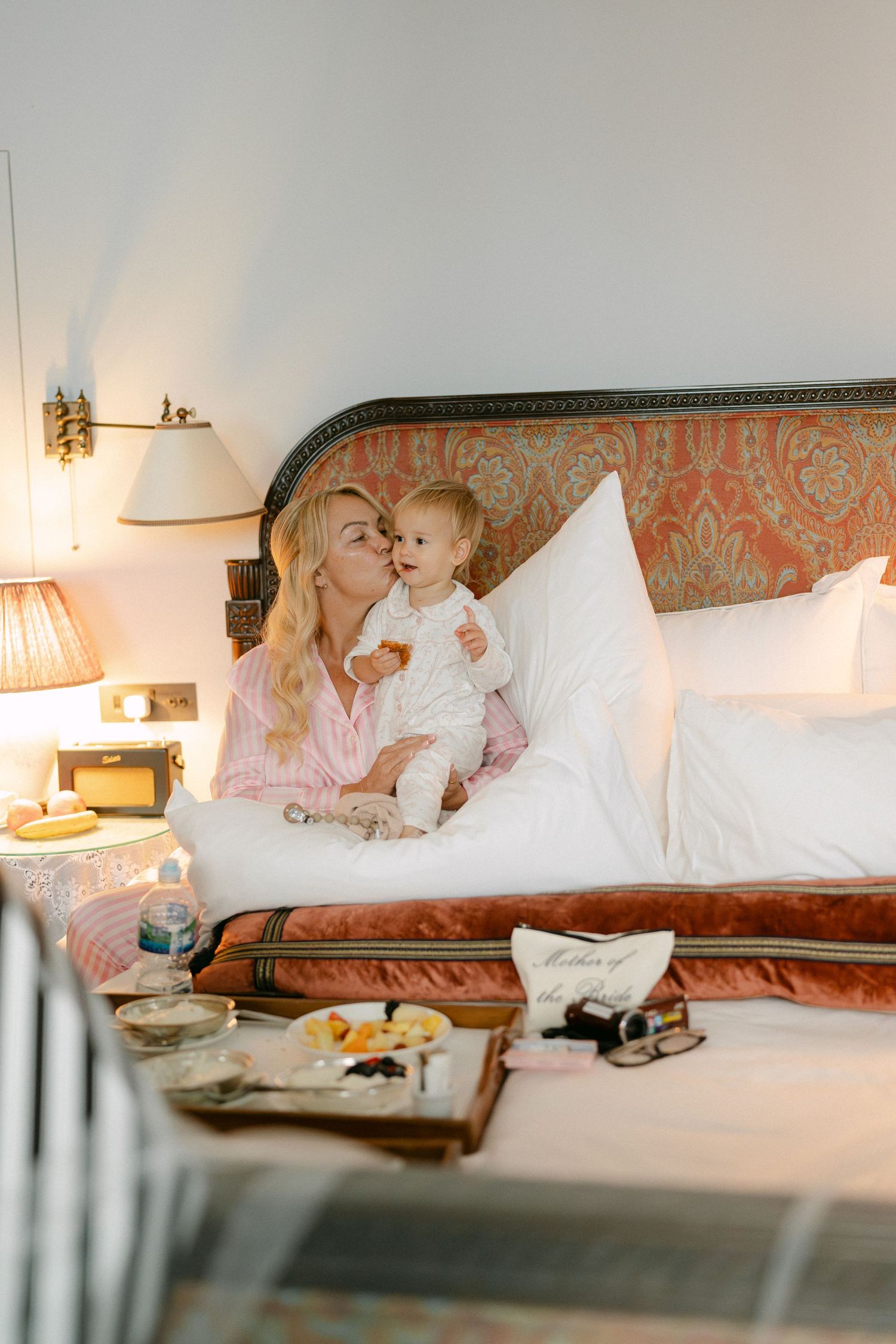 Cozy bedroom scene with pink and white decor and soft lighting.