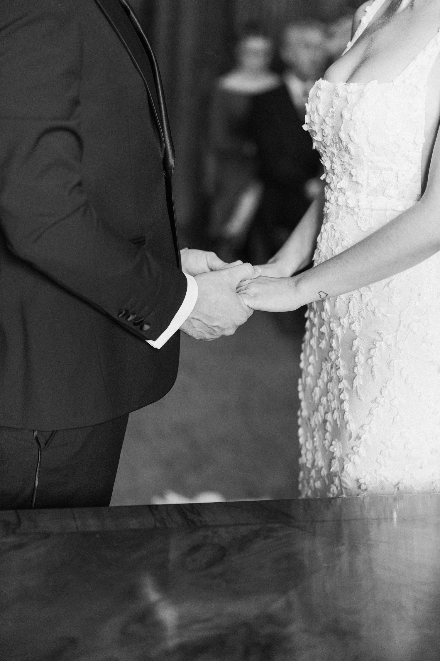 Close-up details of a lace wedding dress and formal attire during a ceremony.
