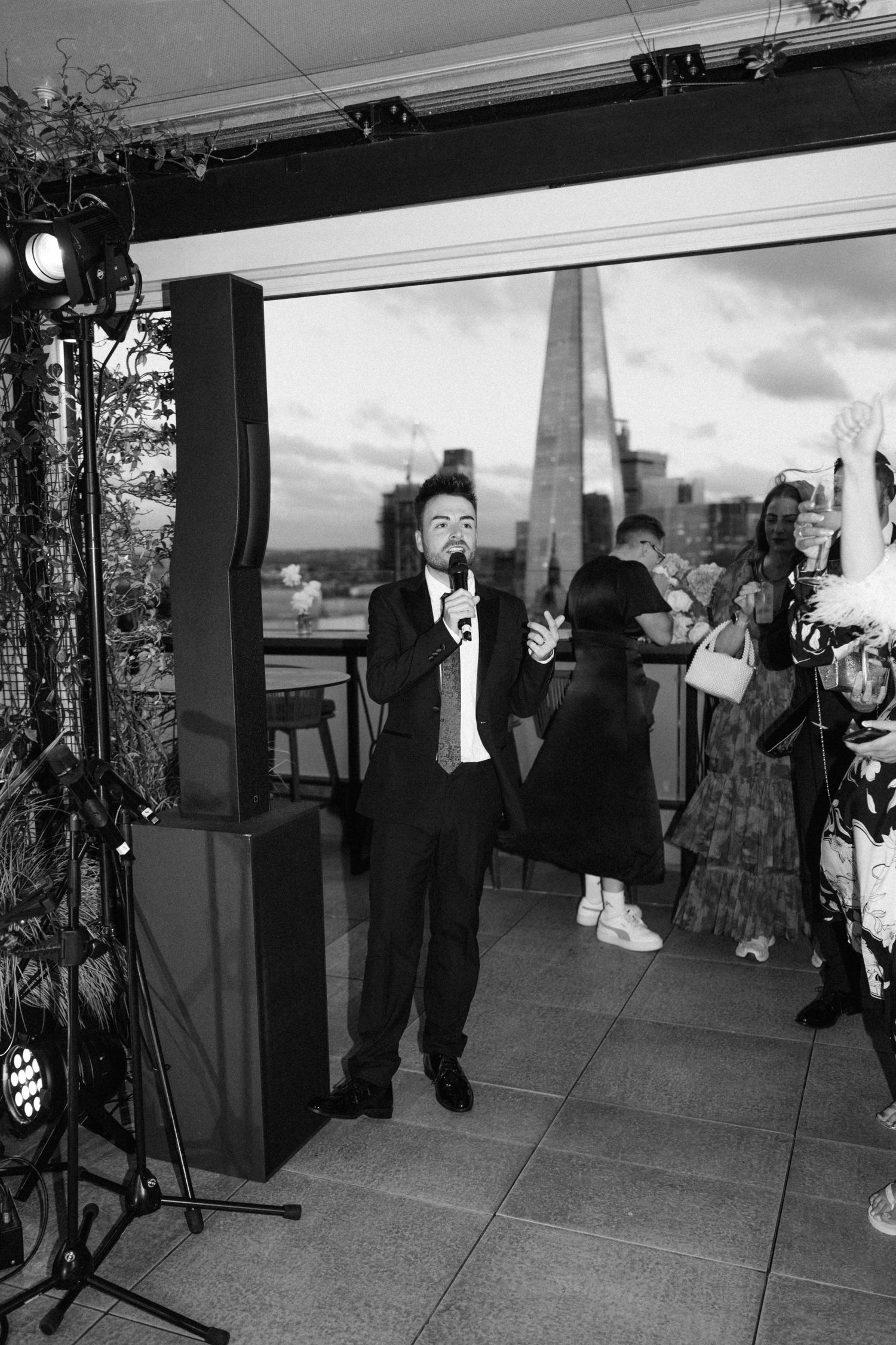 Black and white photo of wedding guests dancing and celebrating in a reception space.