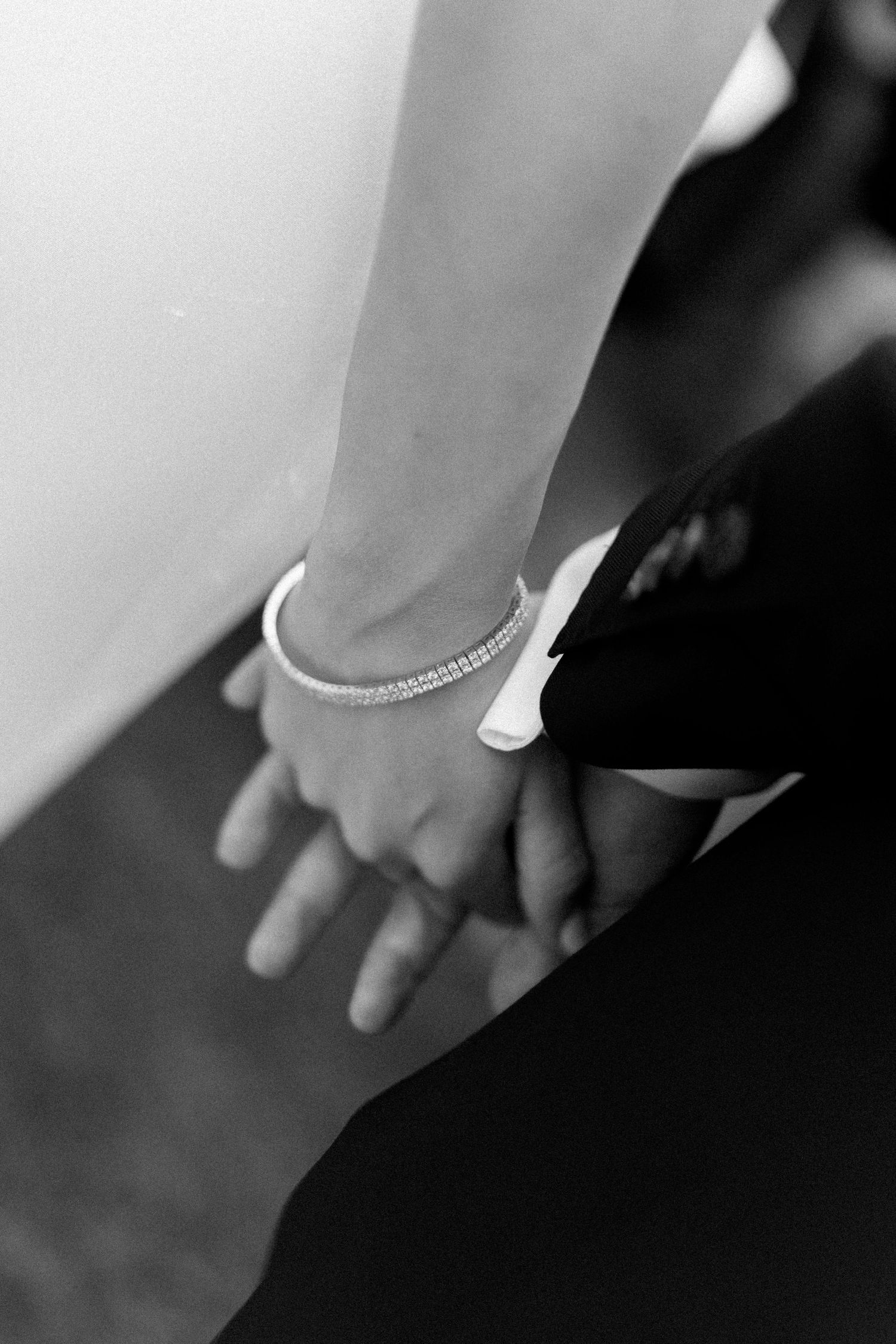 Close-up detail of a delicate bracelet on a wrist against a dark background.
