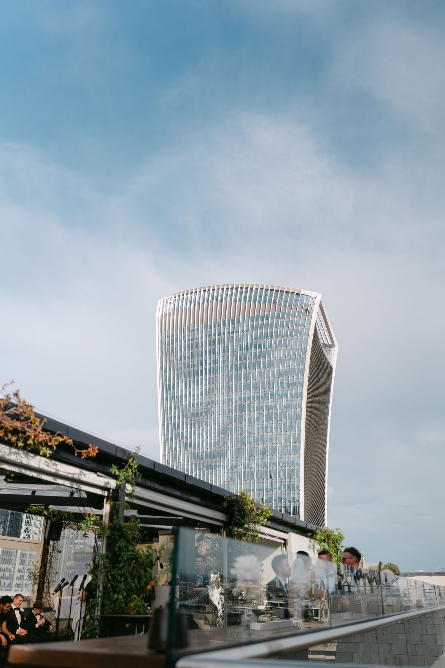 Modern glass office building rises against cloudy blue sky.