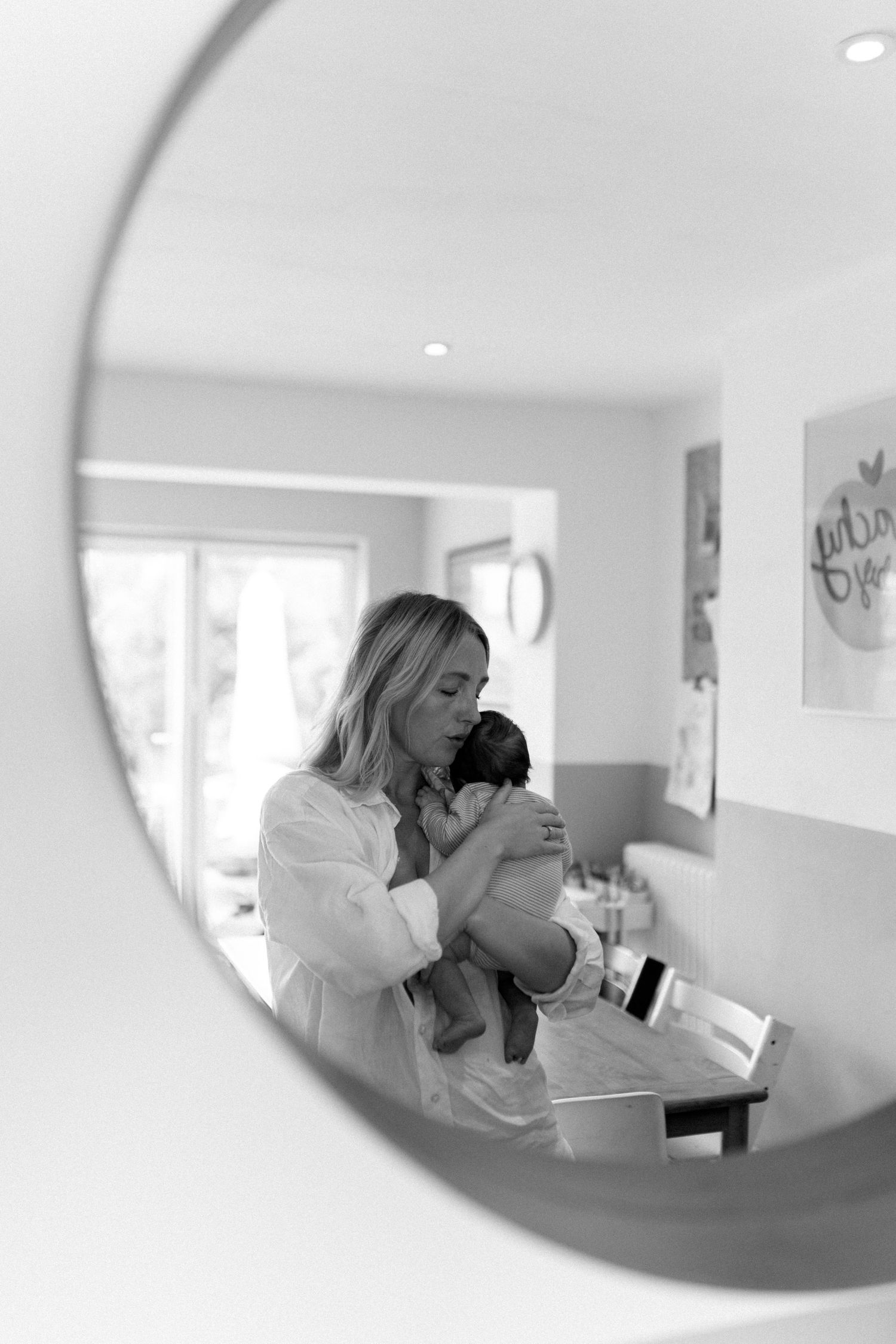A series of black and white photos showing tender moments between parent and child in a bright interior setting.