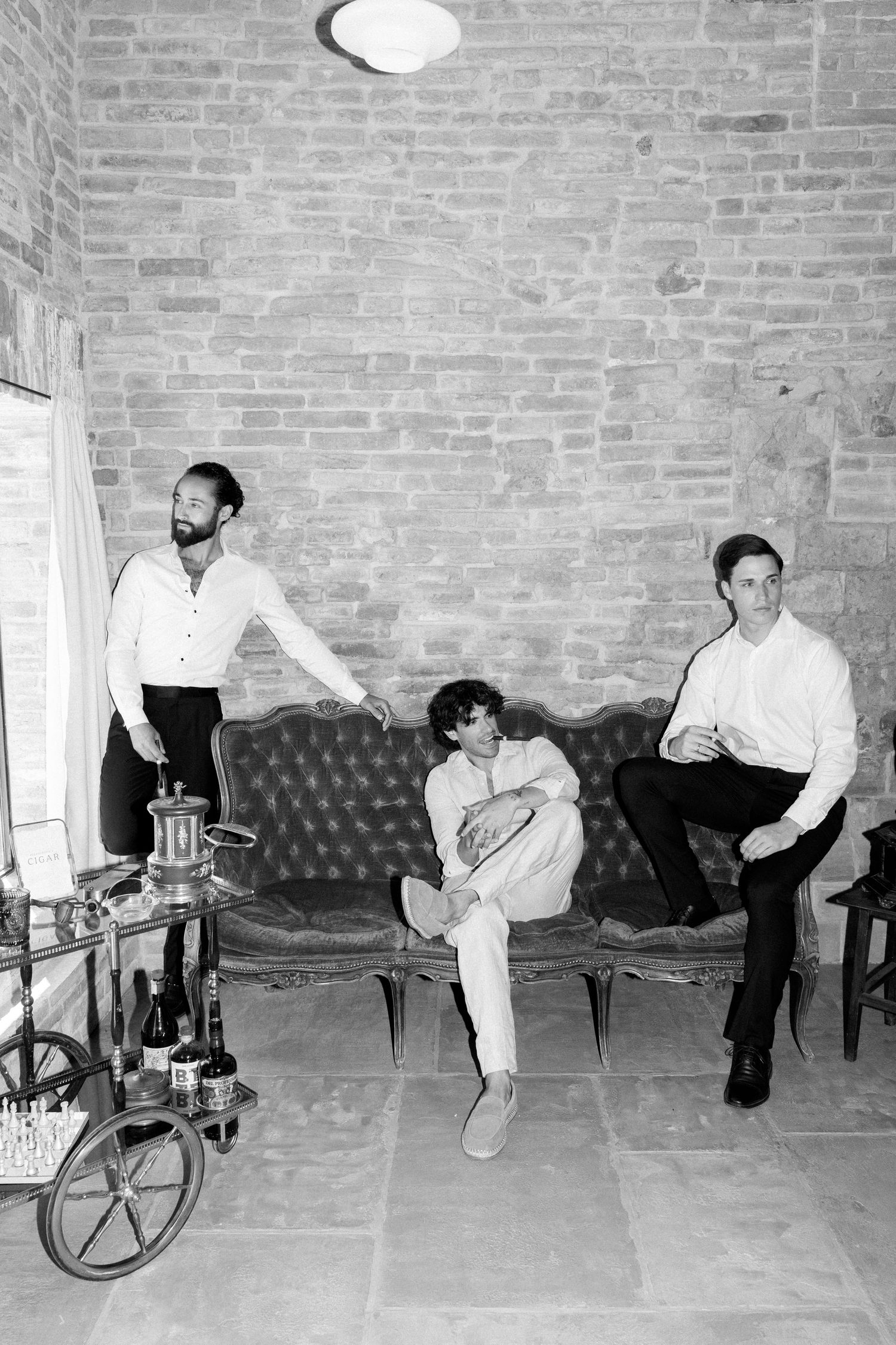 Group relaxing on vintage leather couch against brick wall with unicycle visible.
