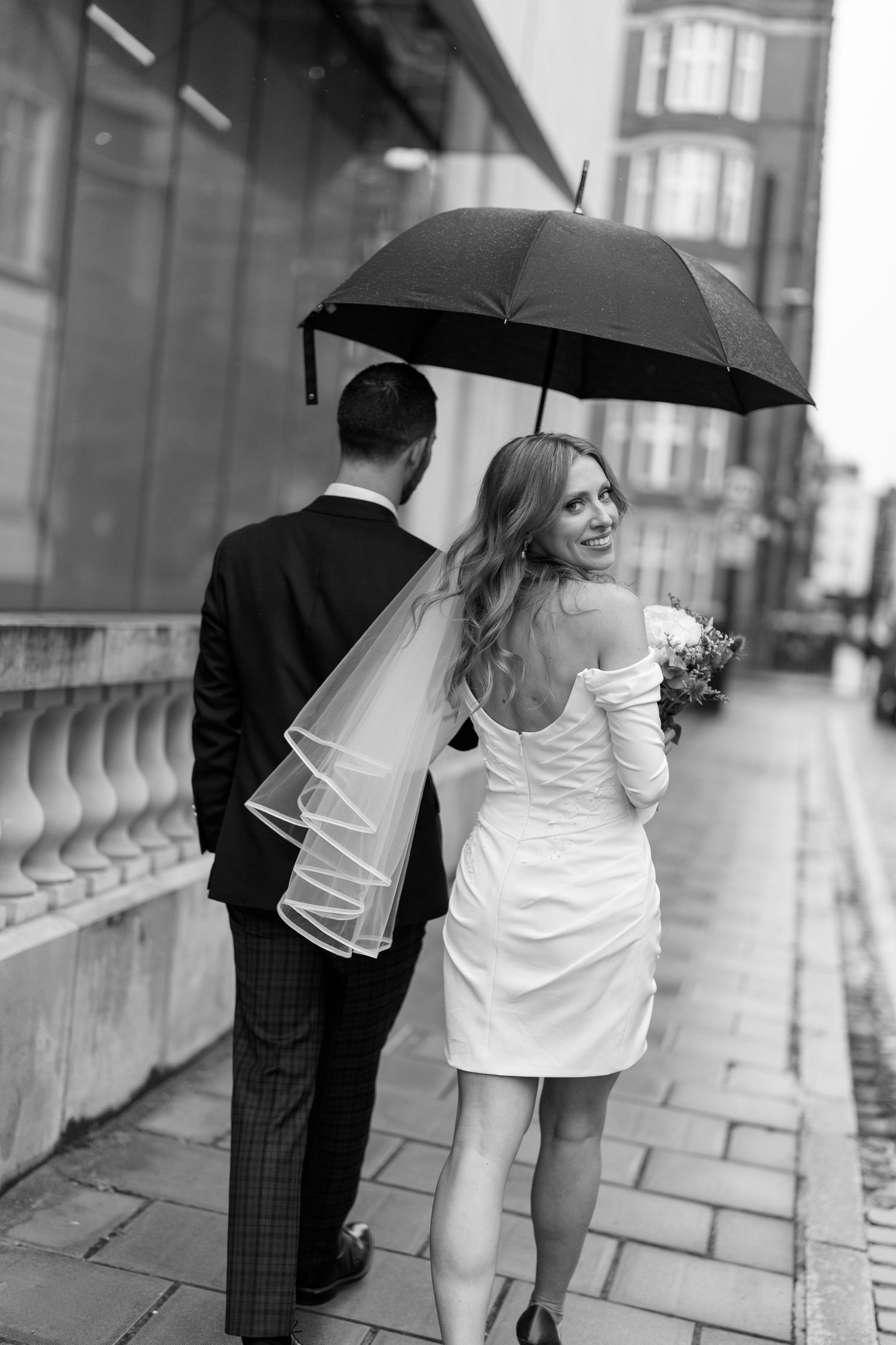 A sequence of black and white photos showing a couple walking with umbrellas on a rainy street.