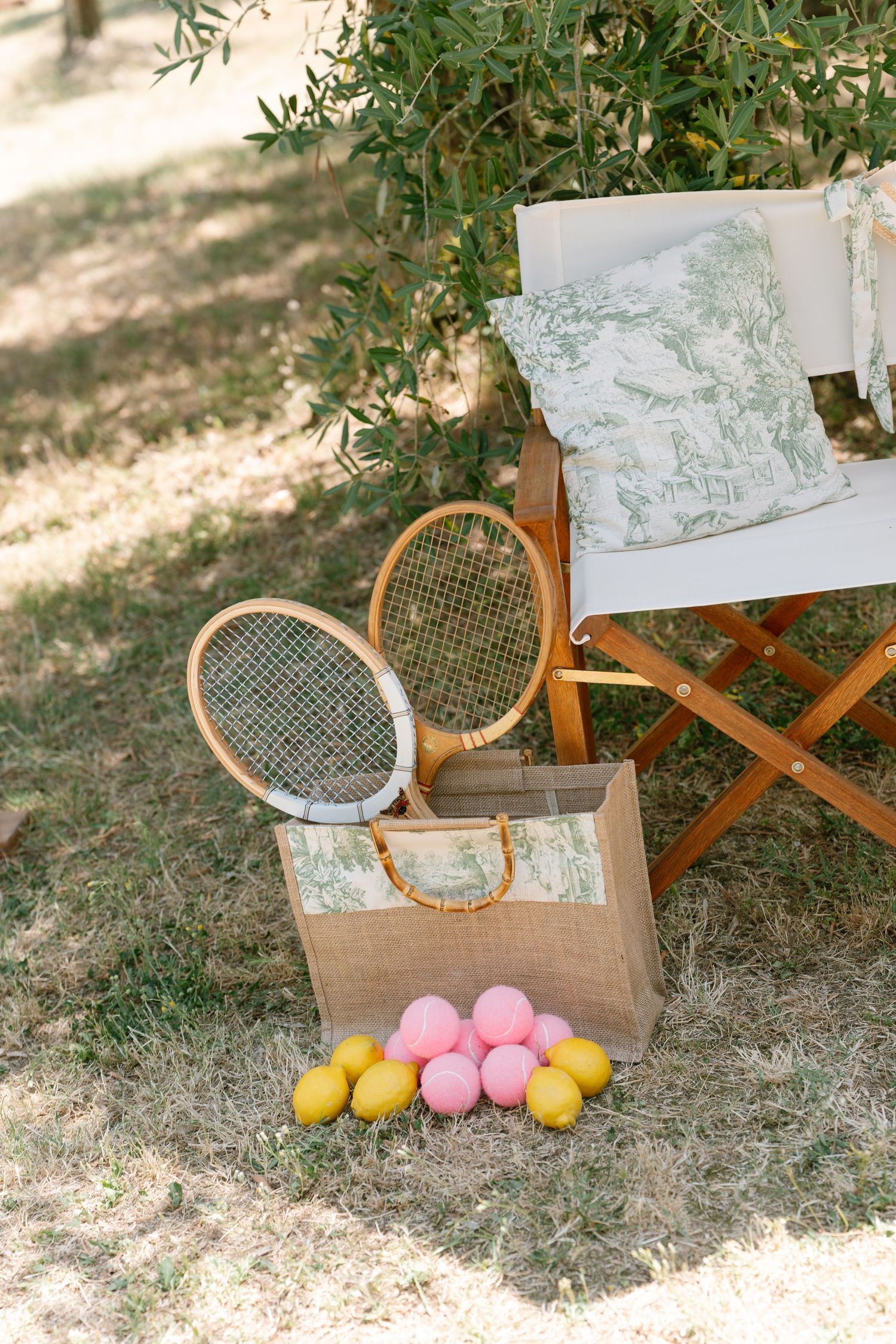 Wooden tennis rackets and colorful balloons arranged in garden setting.