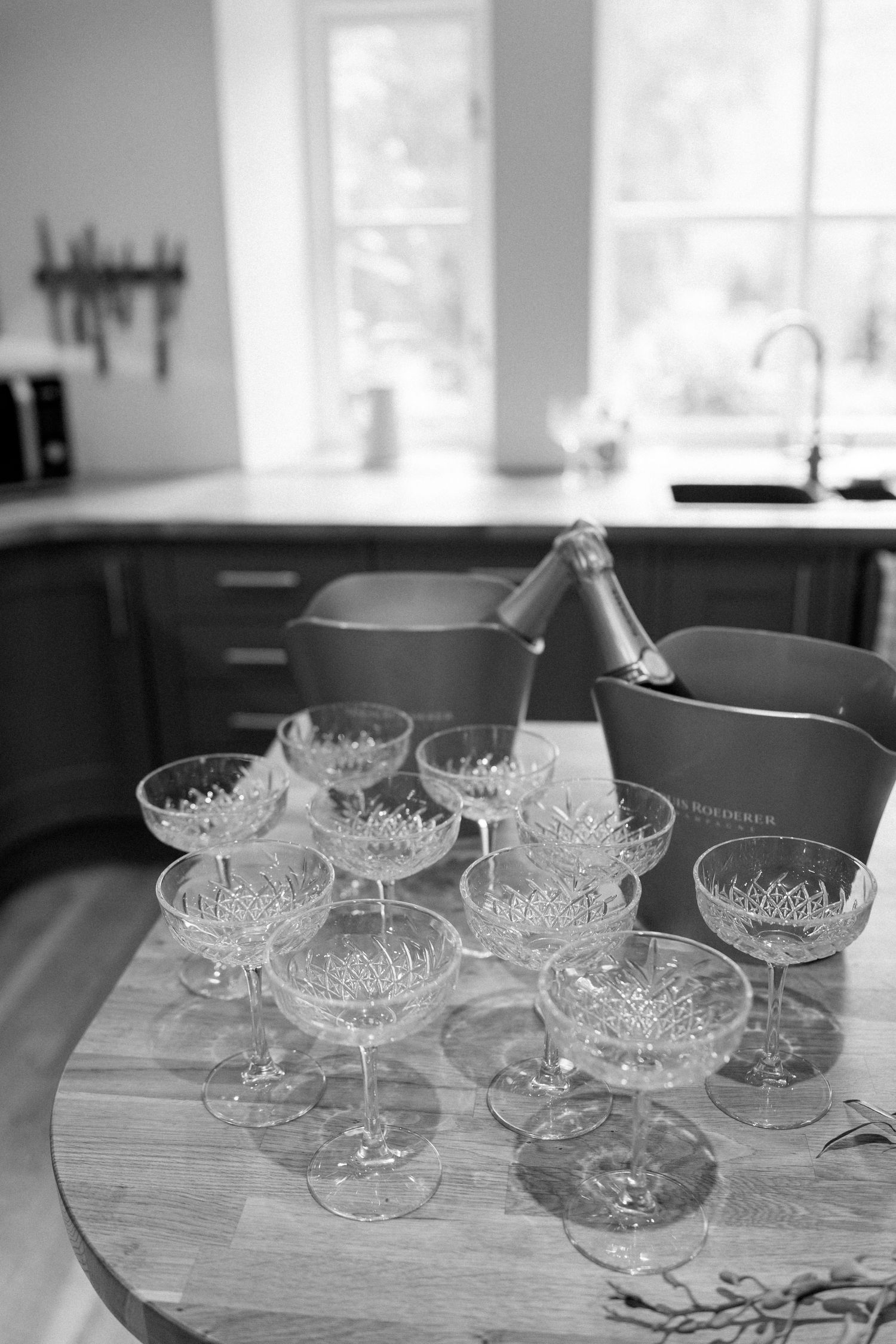 Crystal champagne coupes arranged on a wooden table in natural light.