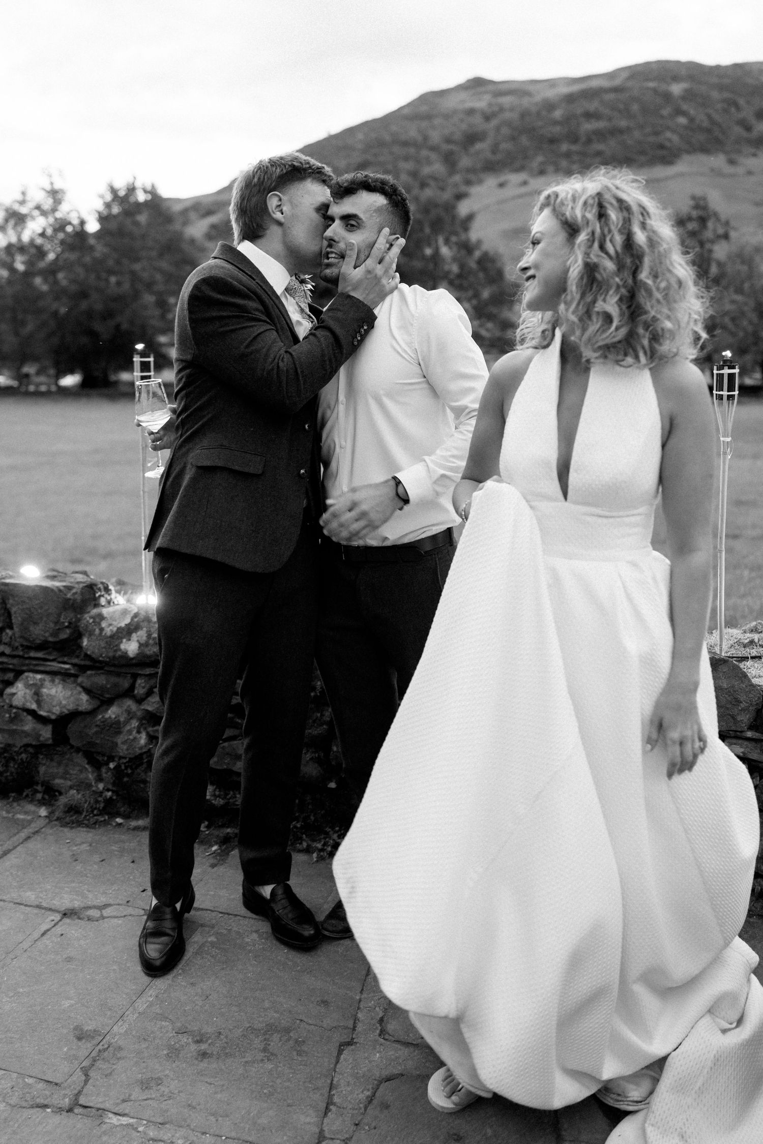 Wedding couple shares candid moments on stone patio with mountain scenery.