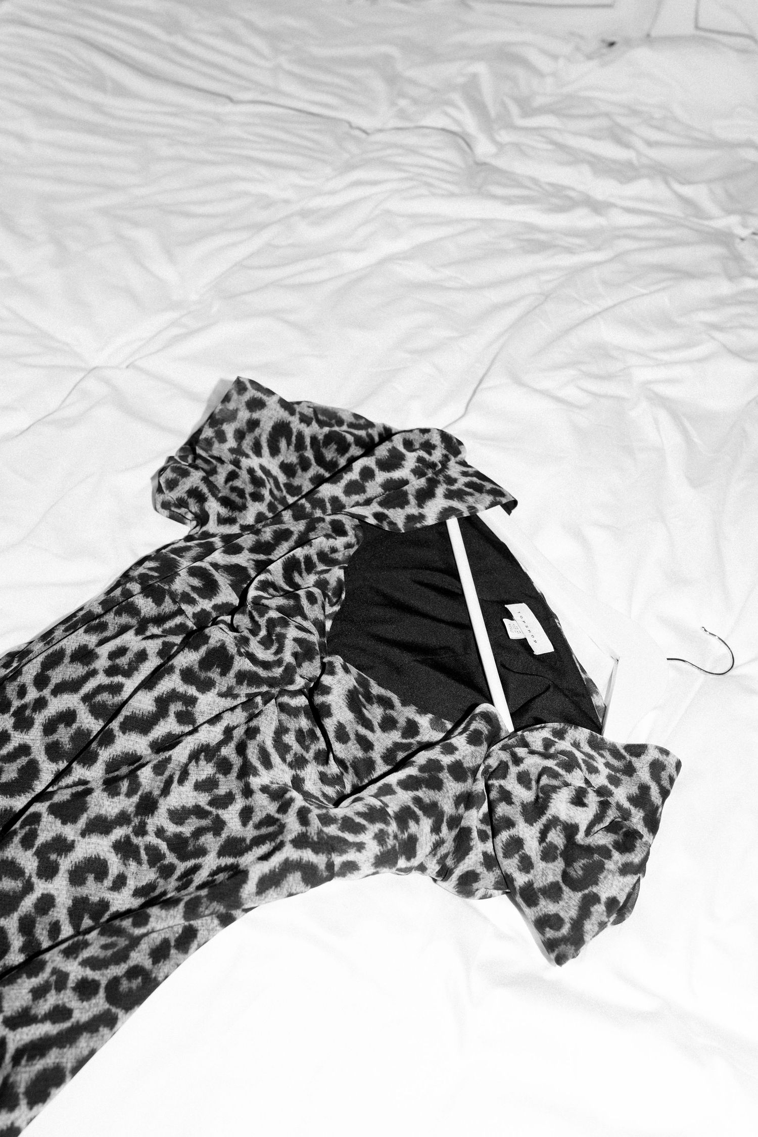 Leopard print fabric laid out on white bedding showing various folds and patterns.