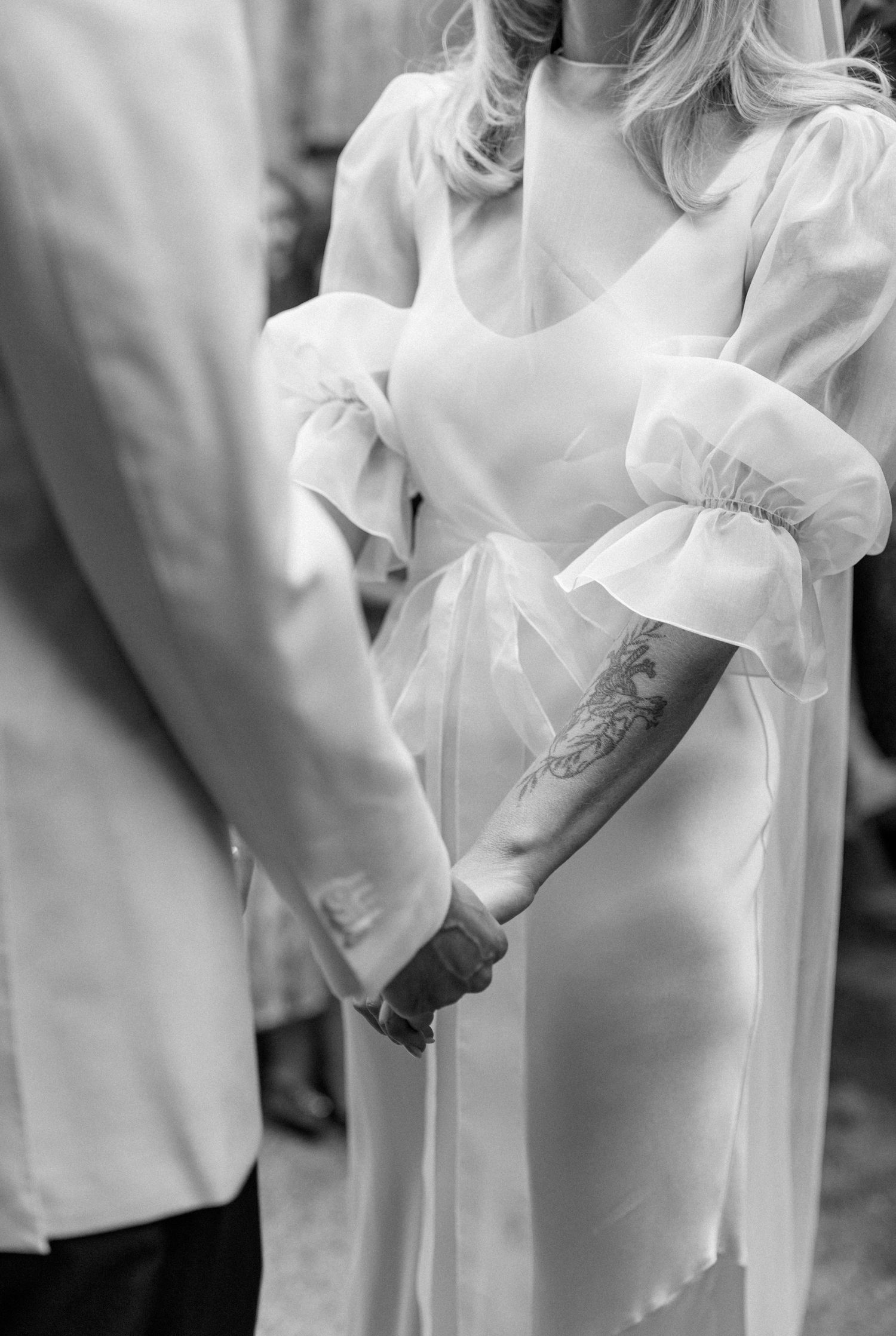 Close-up of elegant white wedding attire details in black and white photography.