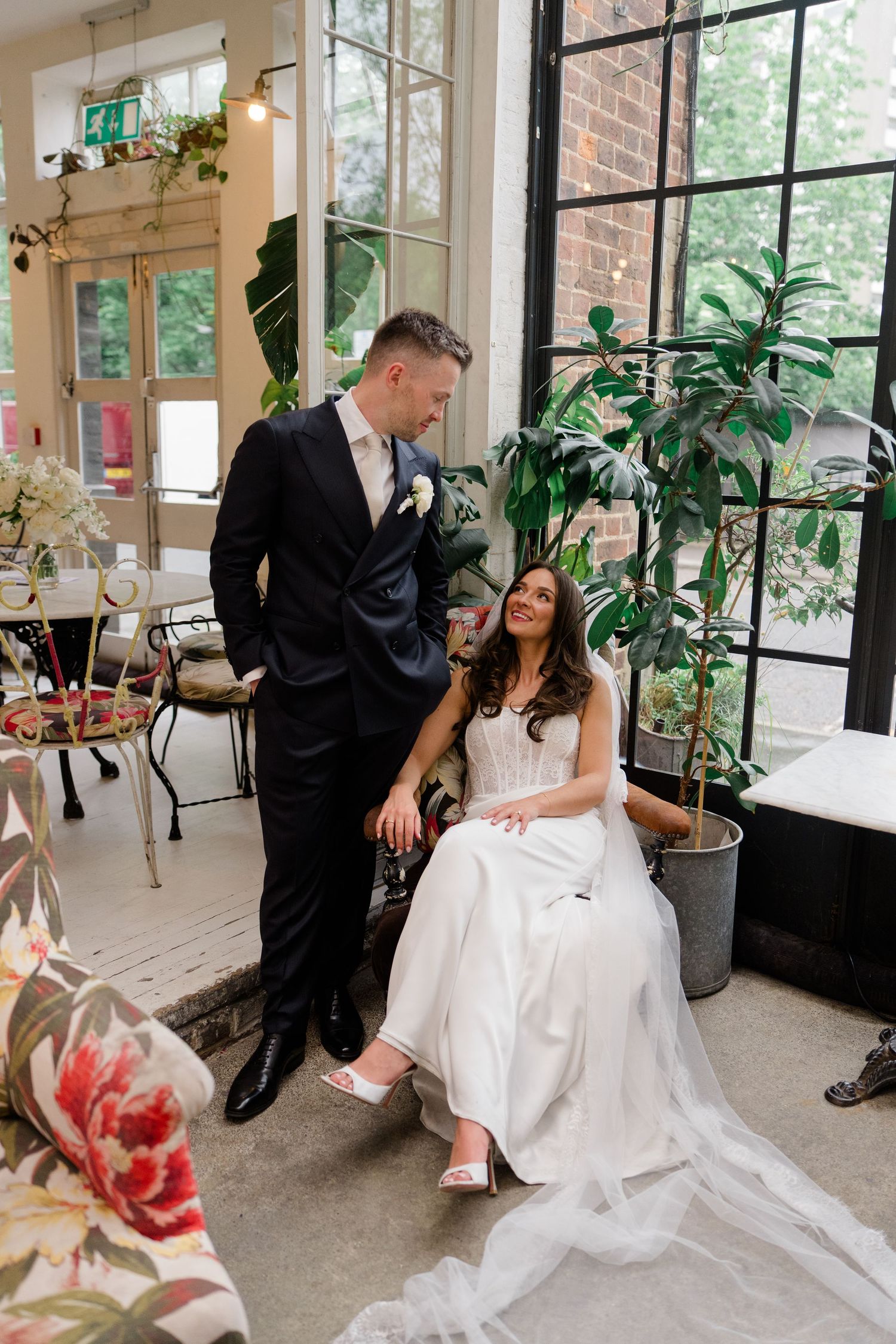 Bride and groom share a tender moment in a light-filled greenhouse wedding venue.