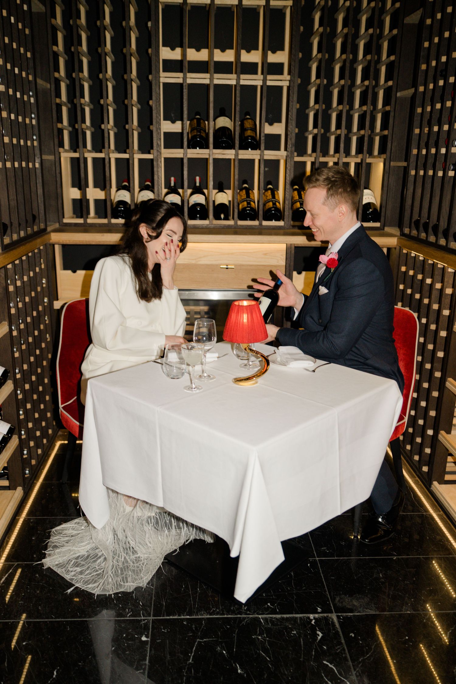 Bride and groom share a joyful moment dining in a wine cellar restaurant on their wedding day.