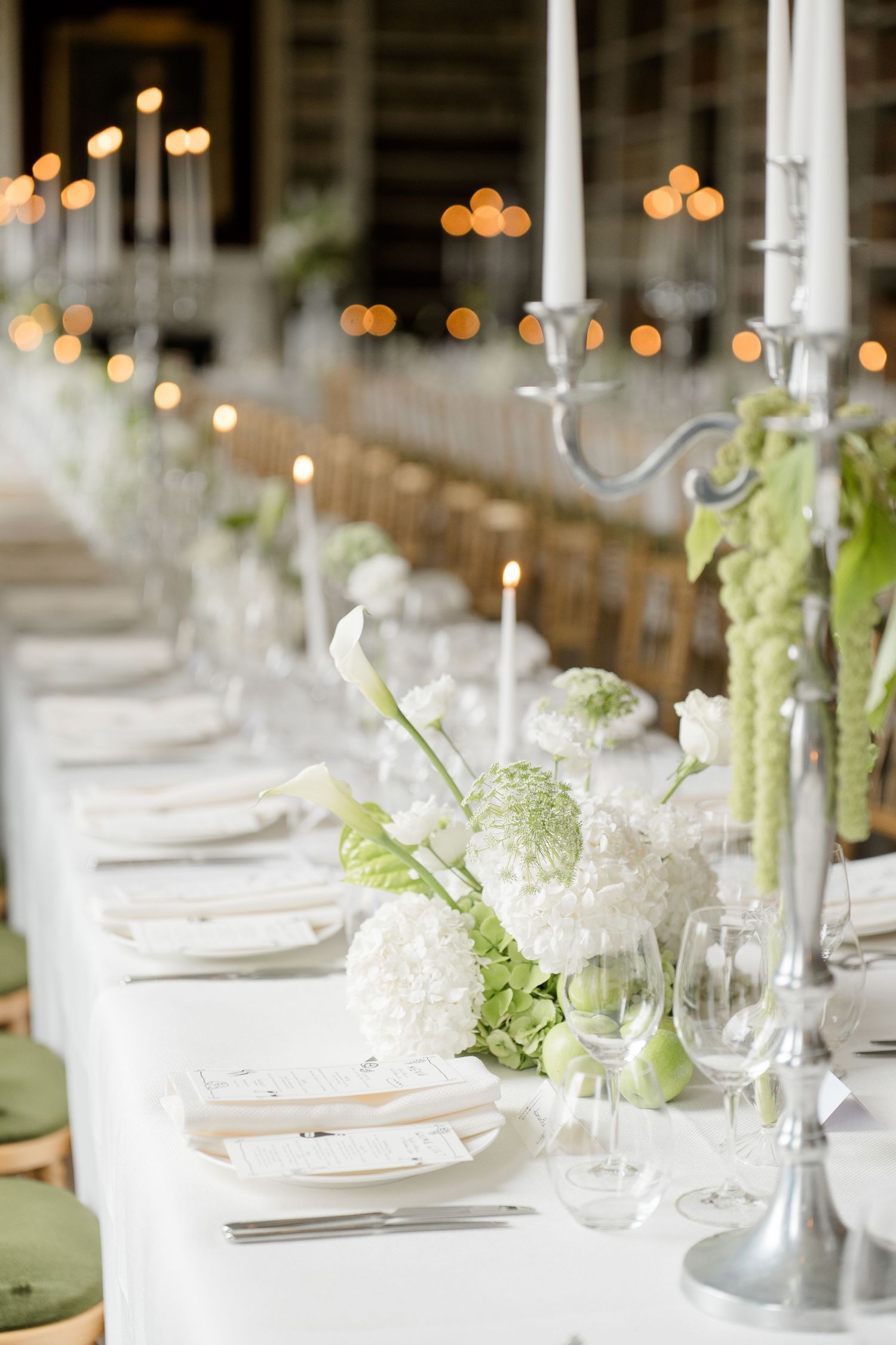 A long reception table elegantly set with white hydrangeas and silver candelabras.