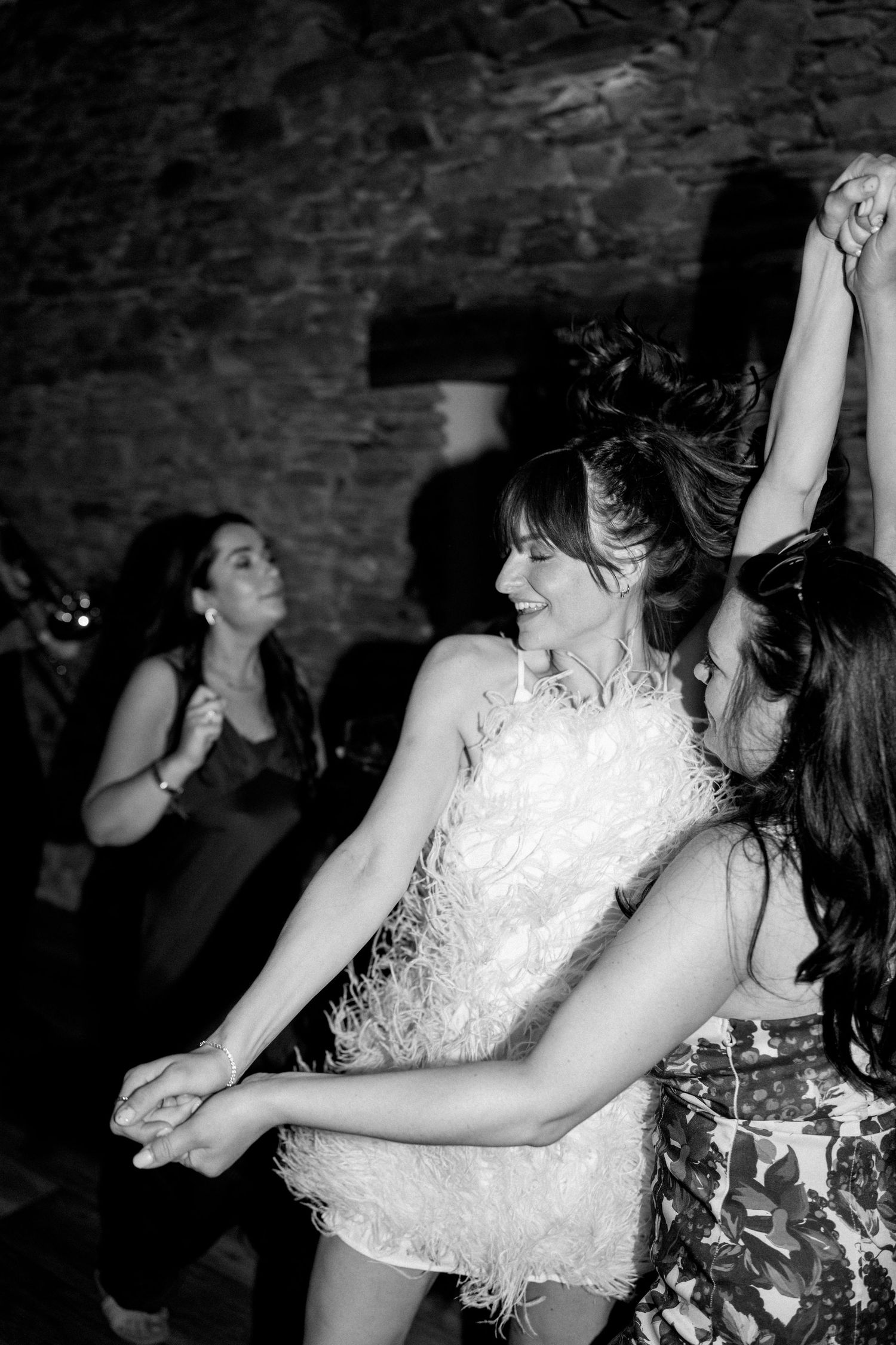 Black and white photo of people dancing at a party in a rustic stone venue.
