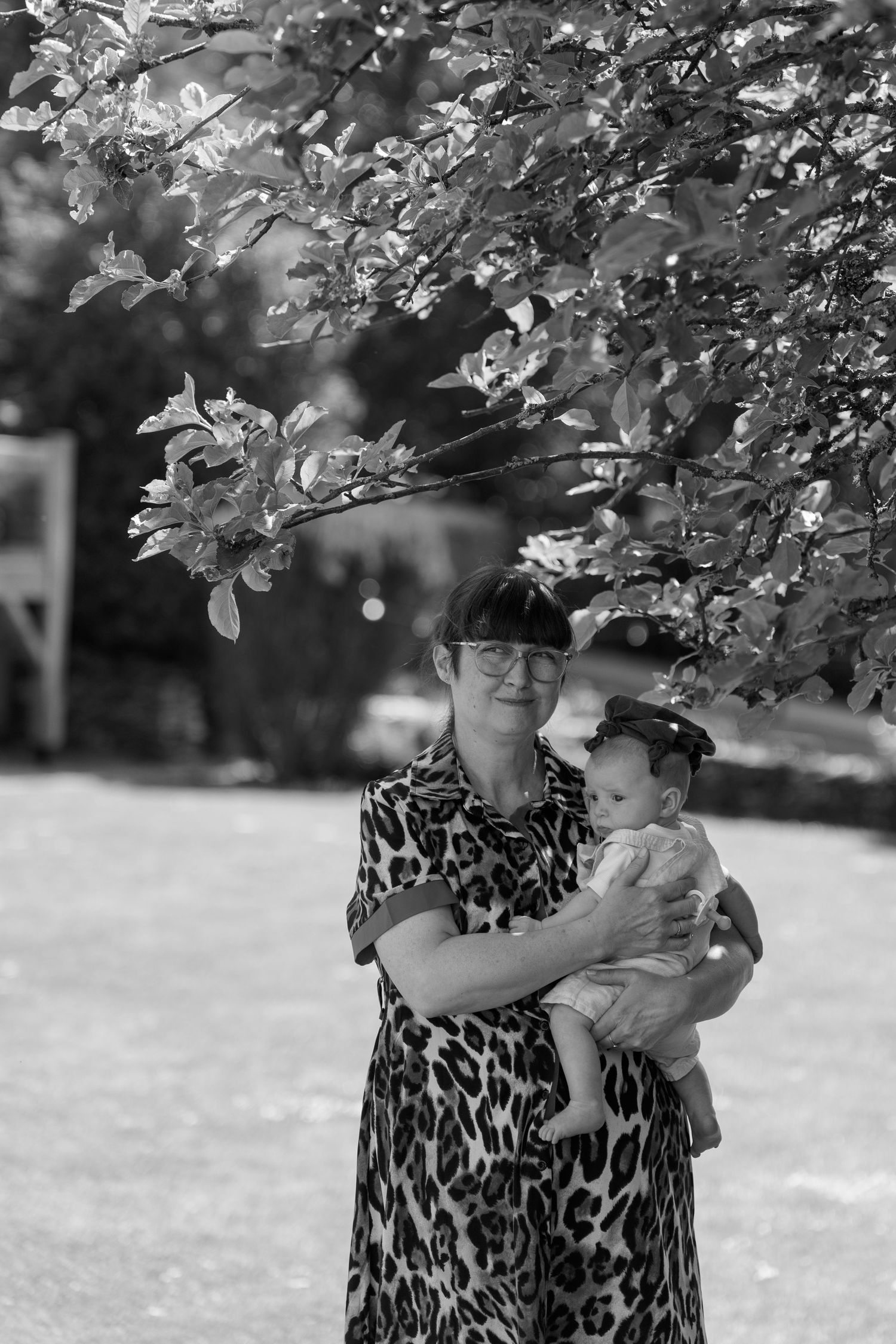 Black and white candid moment of someone wearing a leopard print dress holding a small child.