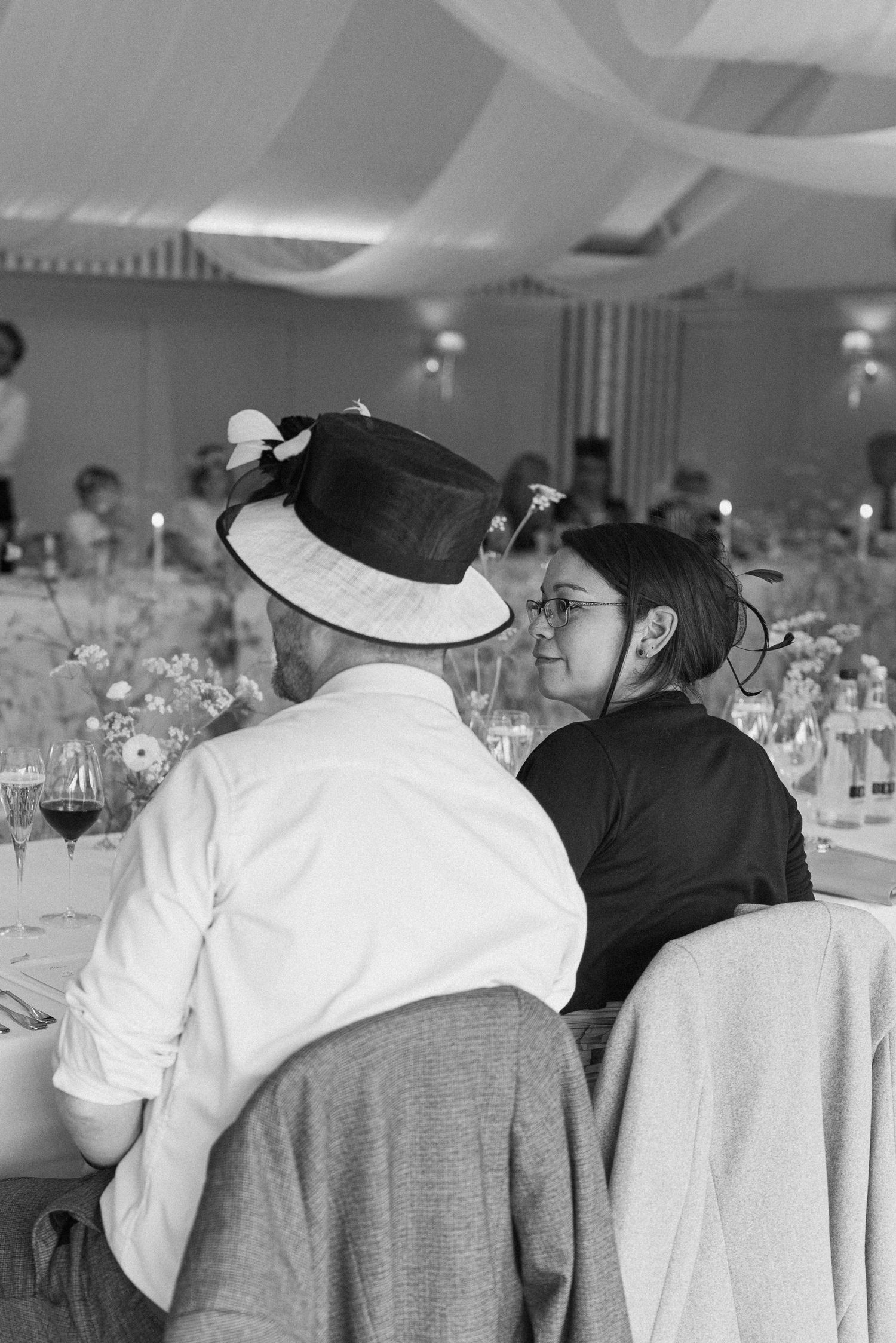 Black and white photo of wedding guests sharing intimate moment at candlelit reception dinner table.