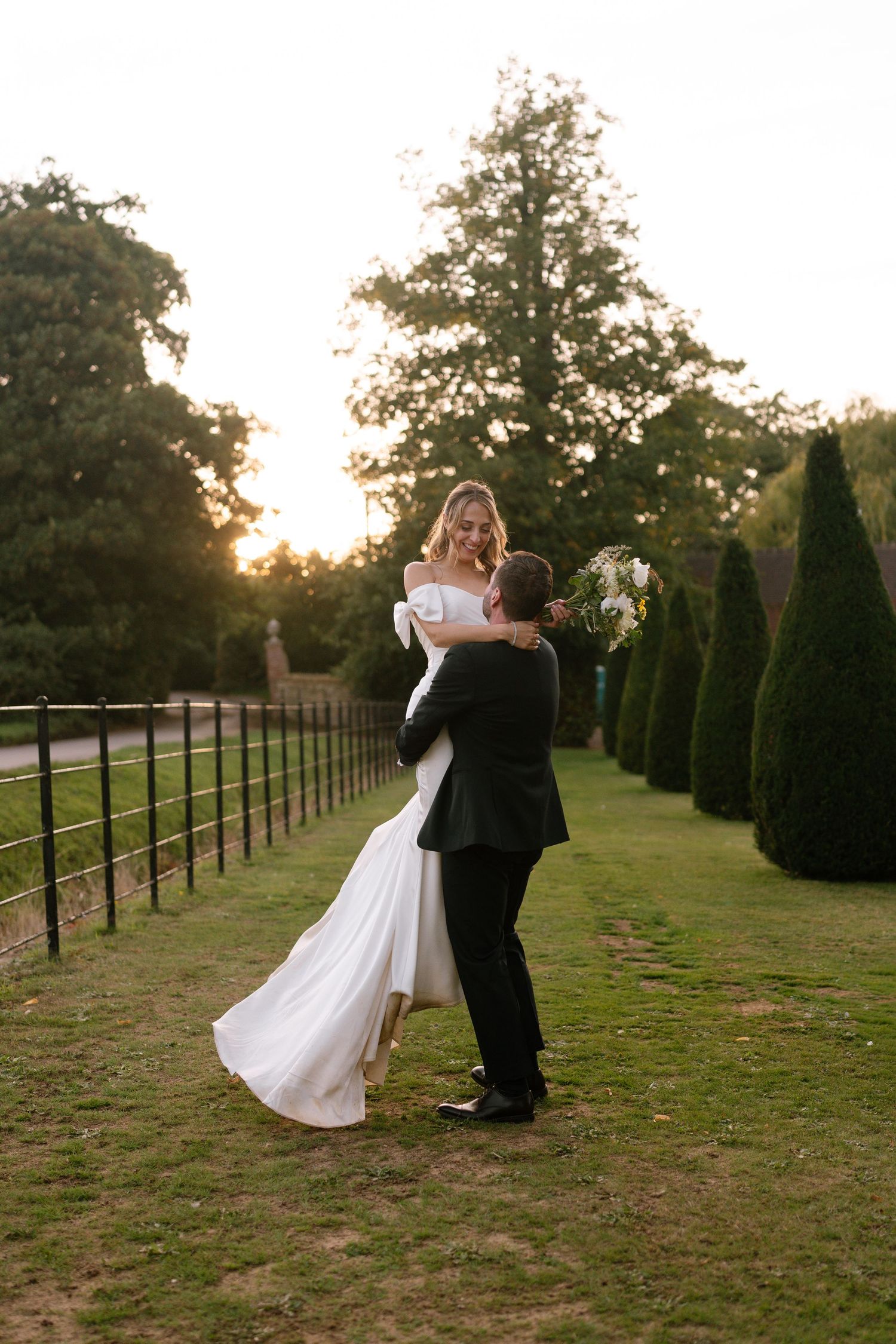 A romantic sunset dance between newlyweds in a garden with topiary trees.