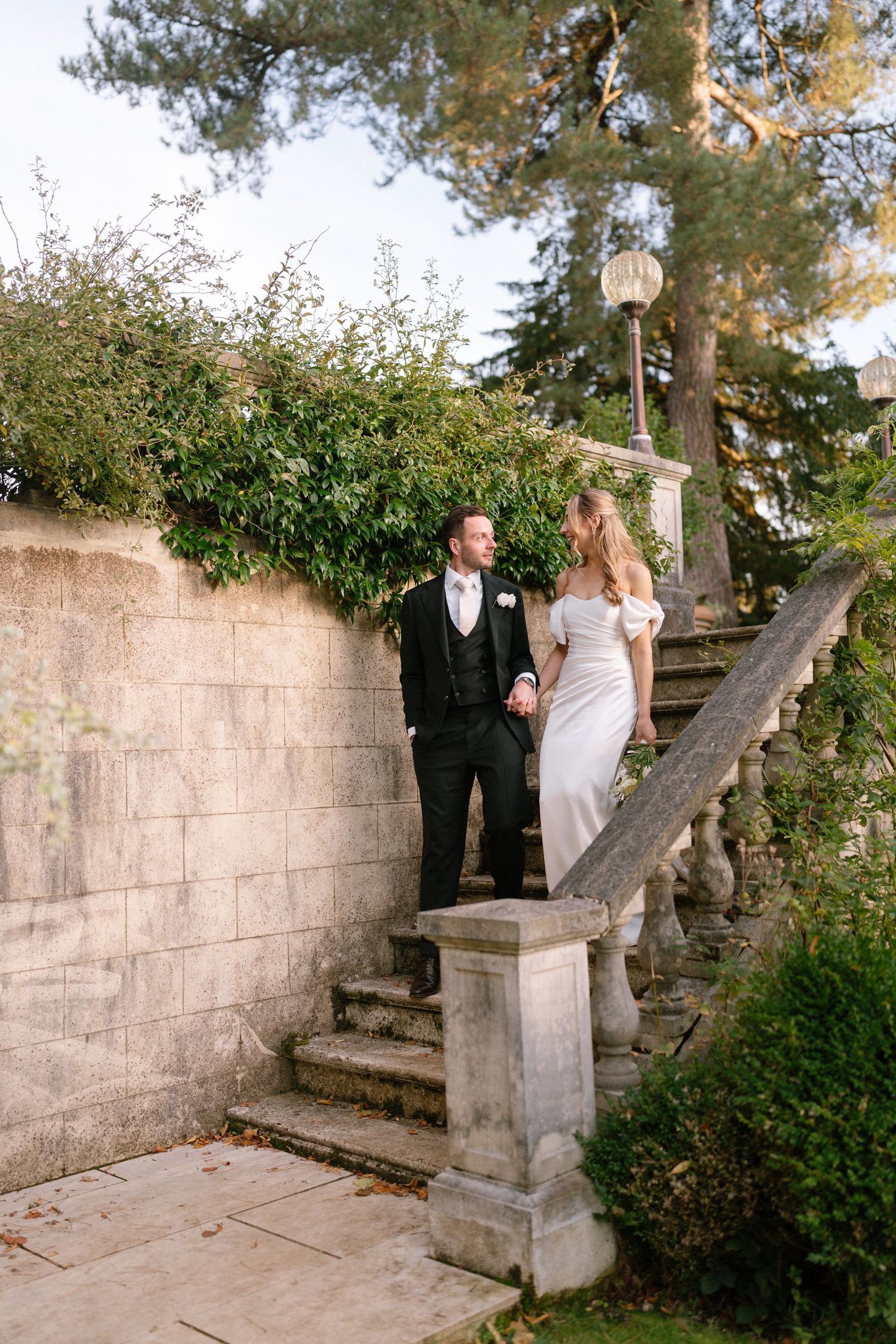 Couple ascending stone garden steps together during wedding photo session.