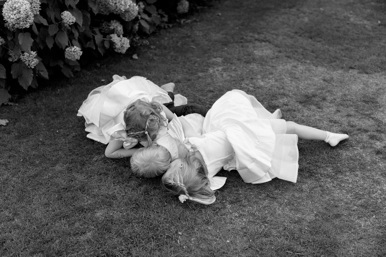 A black and white artistic photo sequence shows people lying on grass in a garden setting.