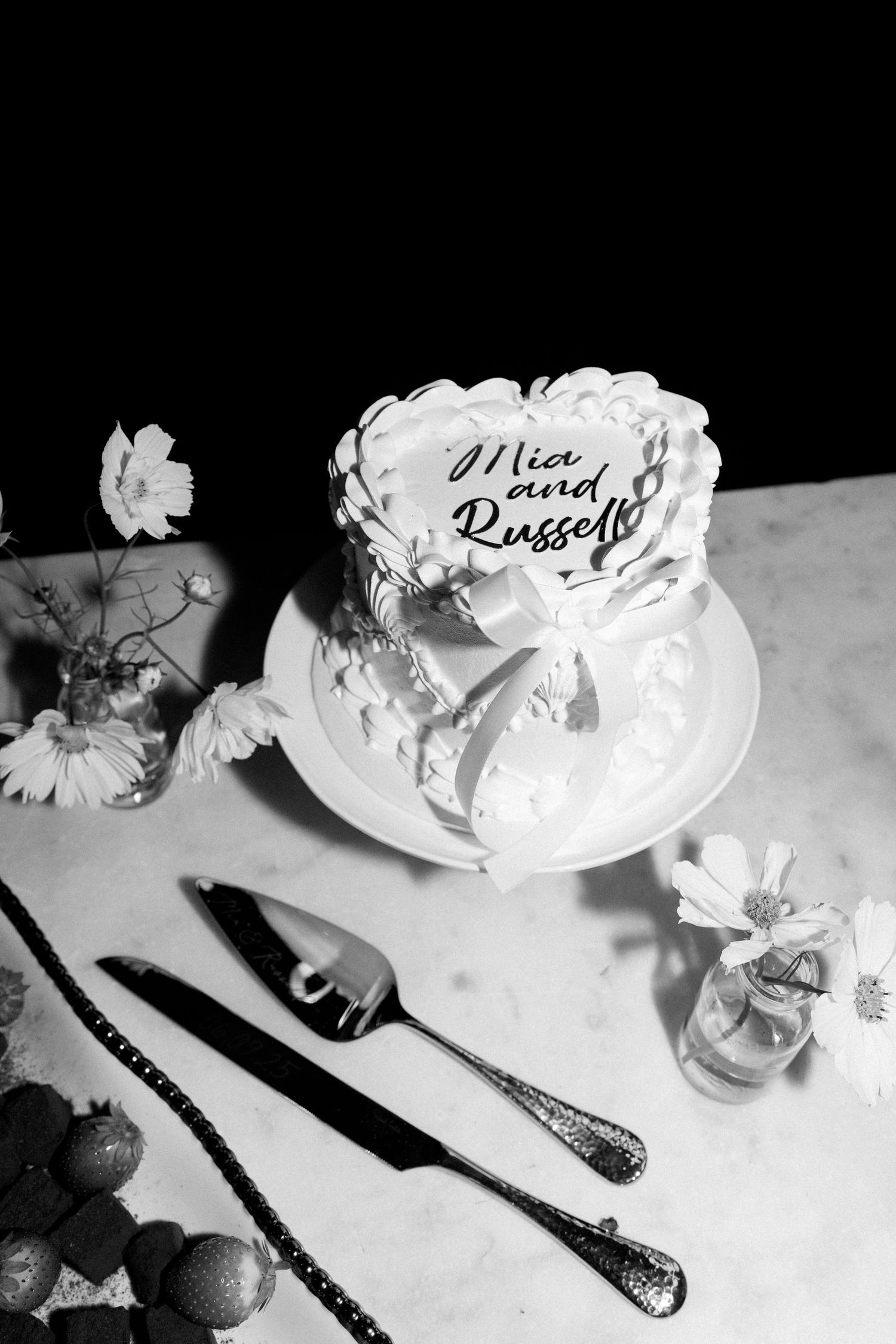Black and white photo of elegant place settings with name cards at a formal dinner.