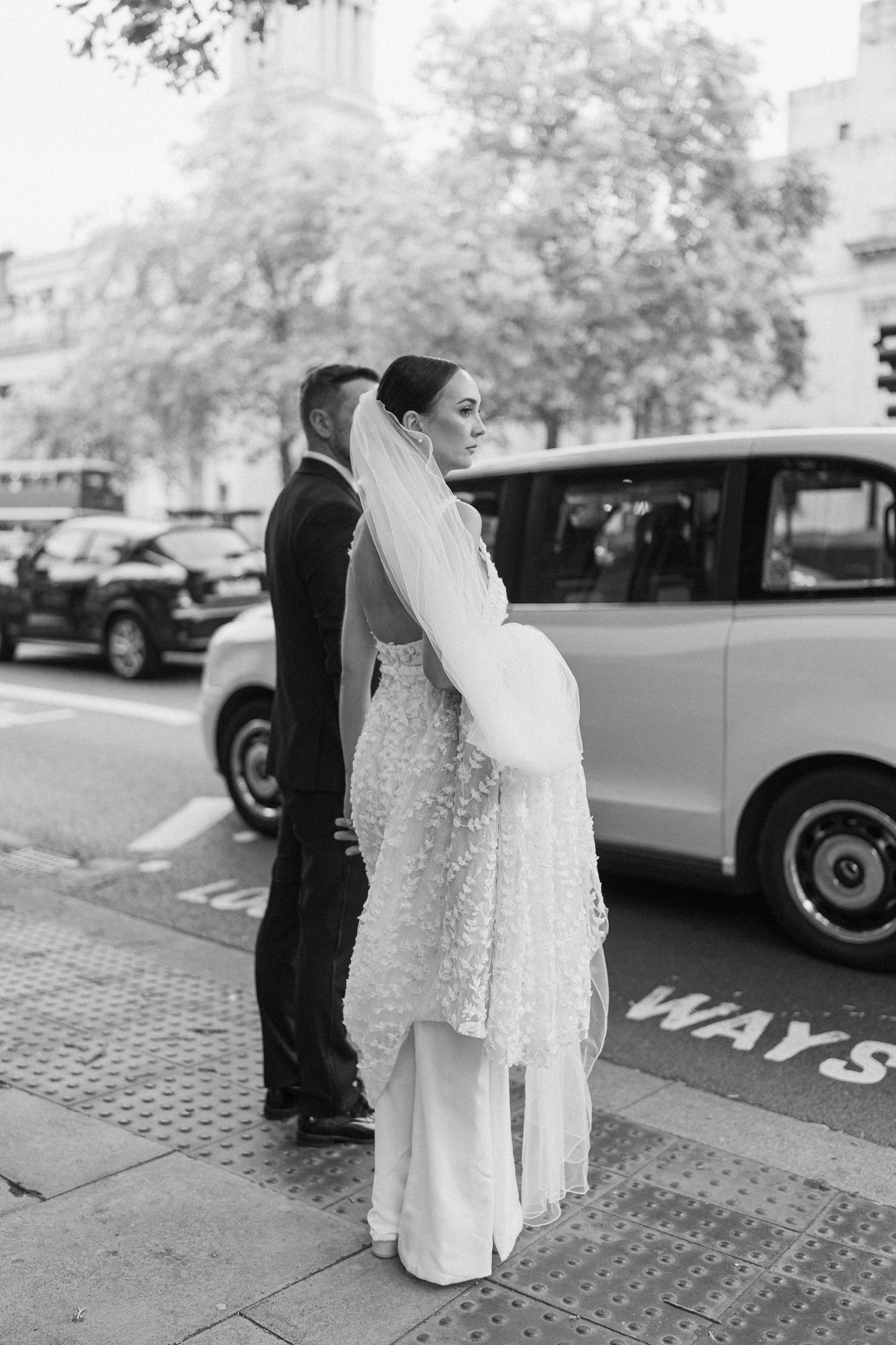 Wedding couple standing near vintage car on London street.
