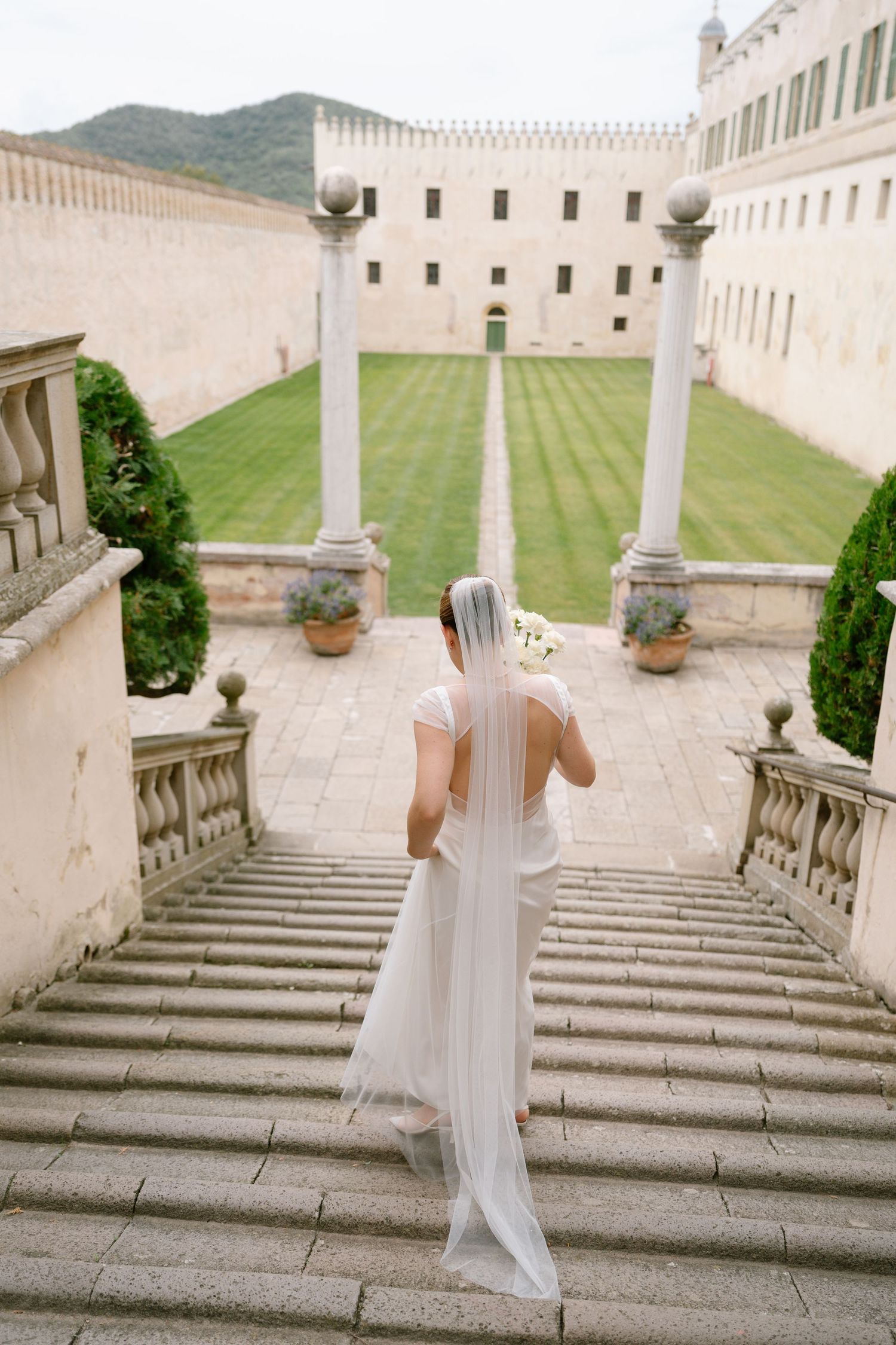 Wedding party descends grand stone staircase at historic Mediterranean-style venue.